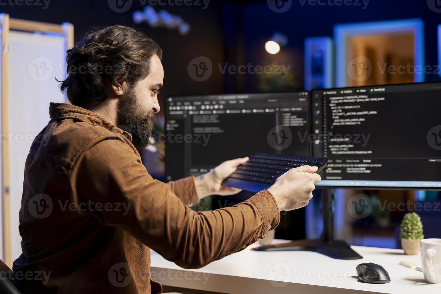 Angry programmer trying to smash keyboard in frustration after failing to secure company servers from virus attacks. Irritated man releasing pent up emotions, unable to build firewalls protecting data photo