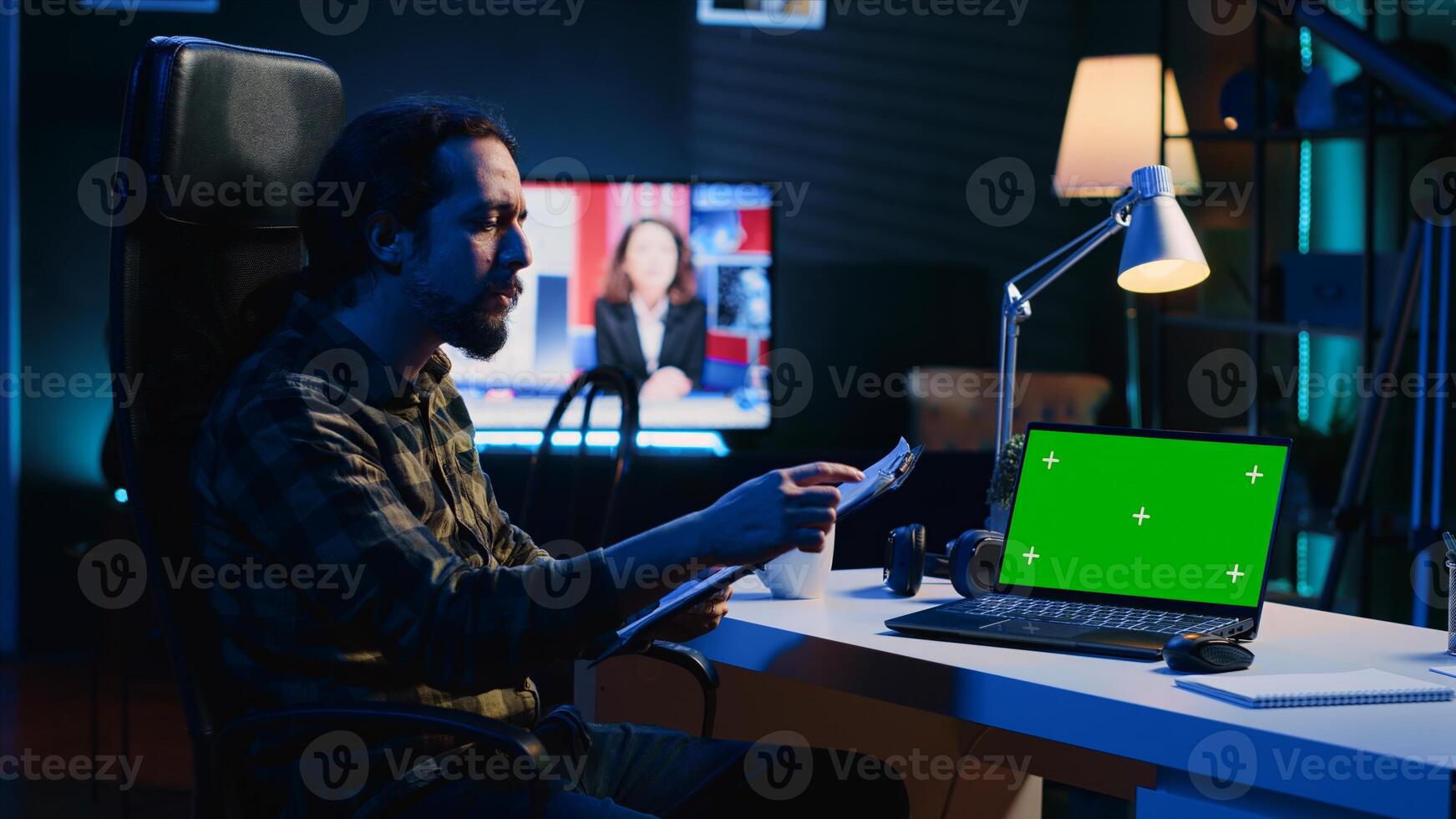 Man in home office checking statistical data financial graphs on documents files, crosschecking with mockup laptop. Remote employee comparing business graphics paperwork with green screen device photo