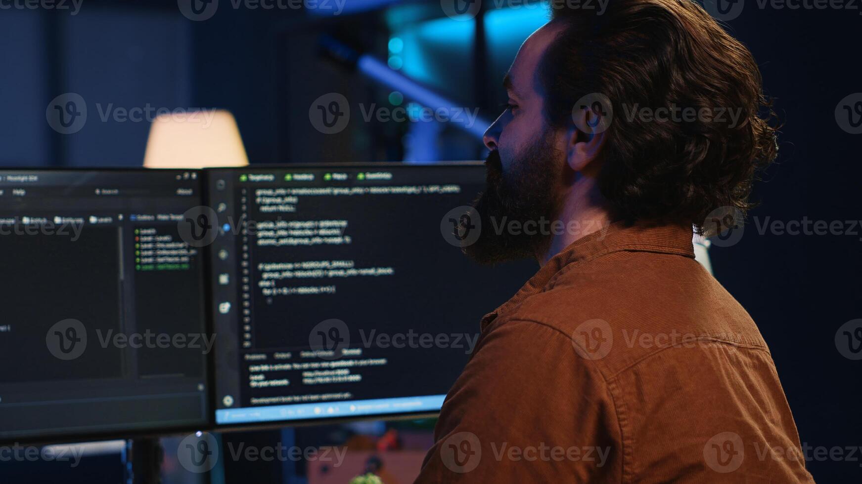 Smiling freelancing developer in home office doing coding on computer at desk. Cheerful IT expert doing contracted job from apartment, writing lines of code at workstation, camera A photo