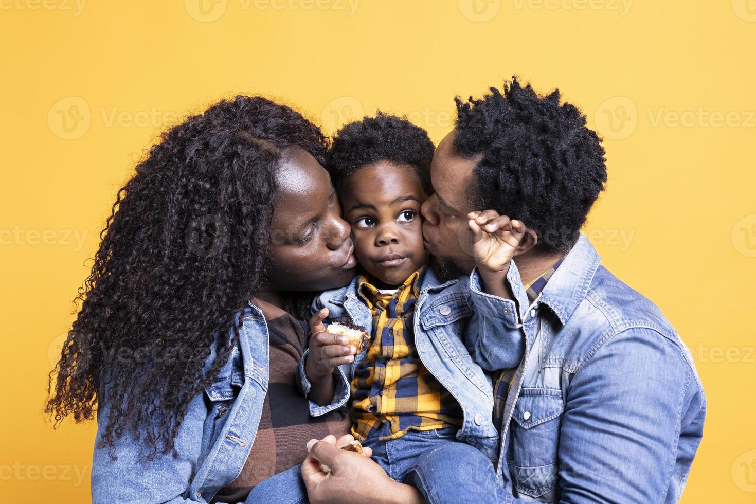 African american proud parents caressing their cute child in studio, feeling lucky an grateful with the their family. Young mom and dad embracing their little infant baby boy against background. photo