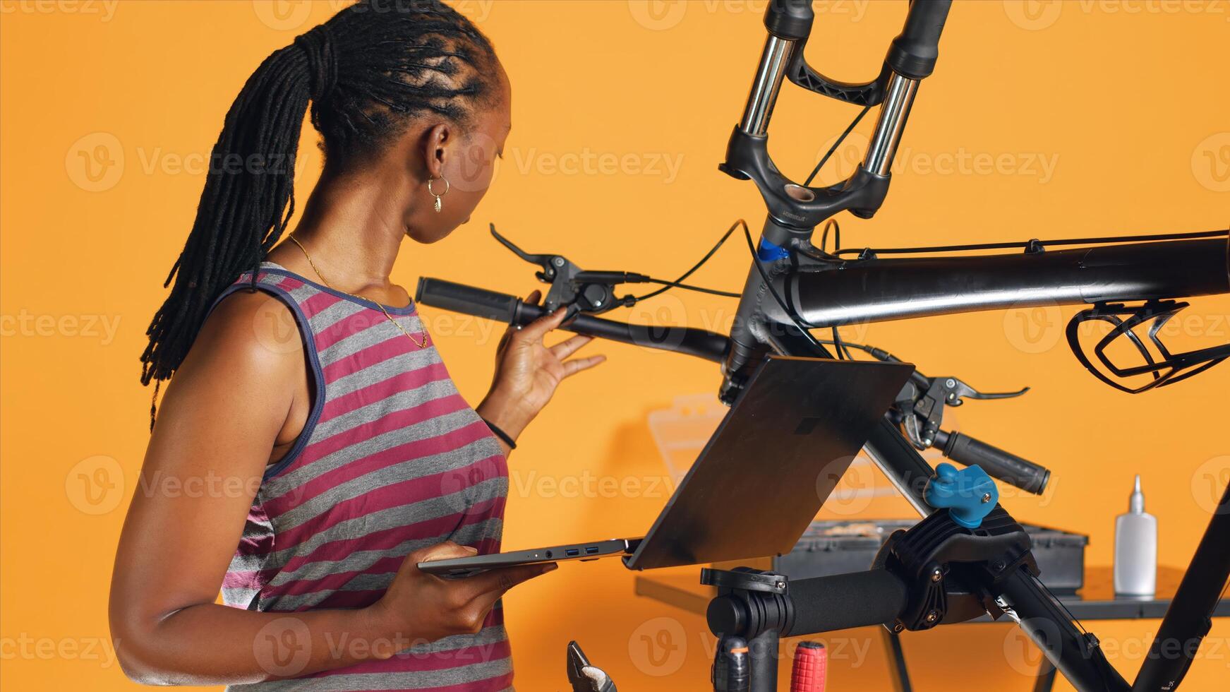 Engineer doing bike servicing in studio background repair shop, searching replacement components online on laptop. Professional looking for necessary work tools for repairing bicycle photo