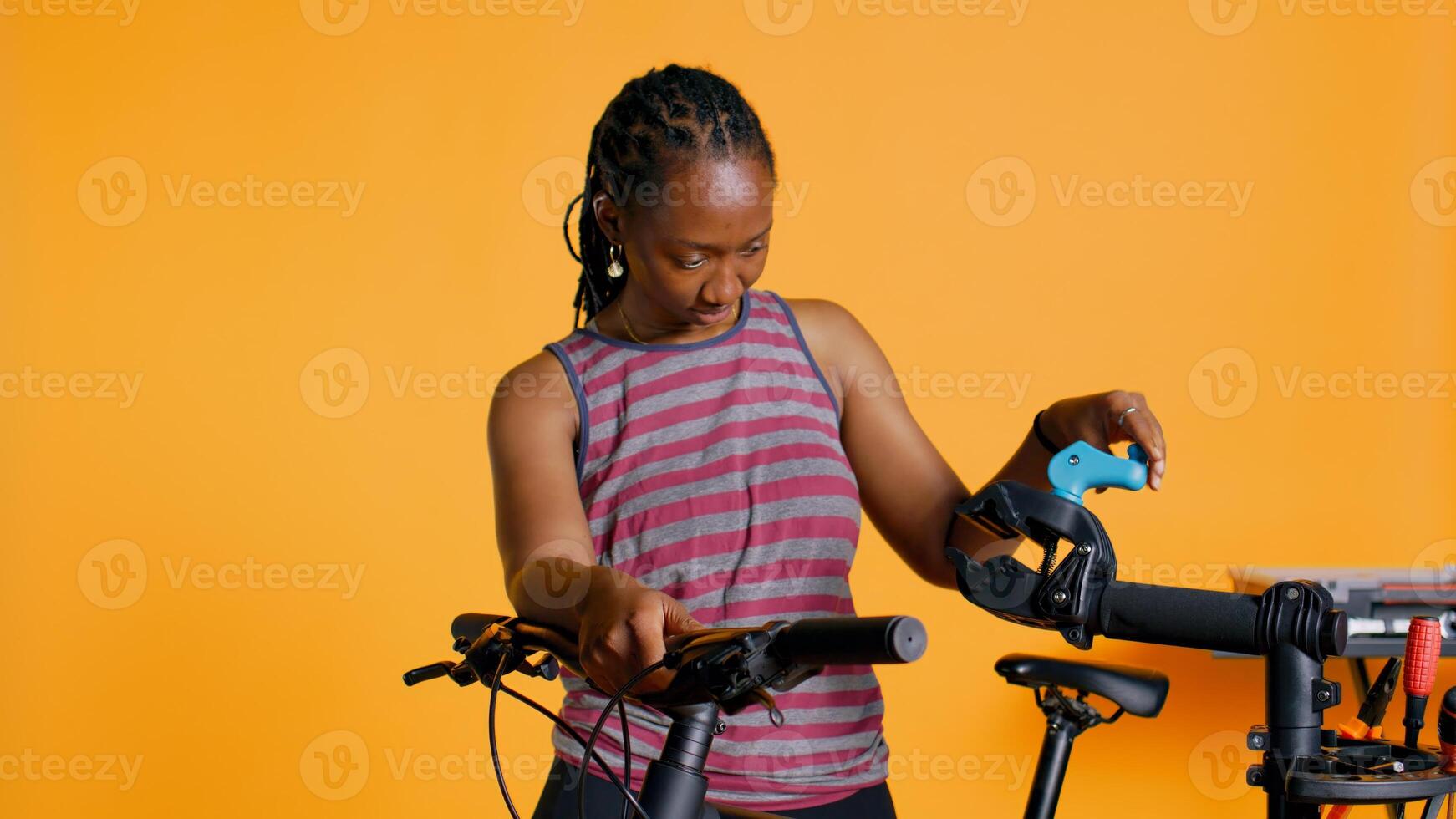 Atelier shop employee setting up bike repair stand before starting work on busted wheels, studio background. Professional securing bicycle on workstand before examining for damages, camera B photo