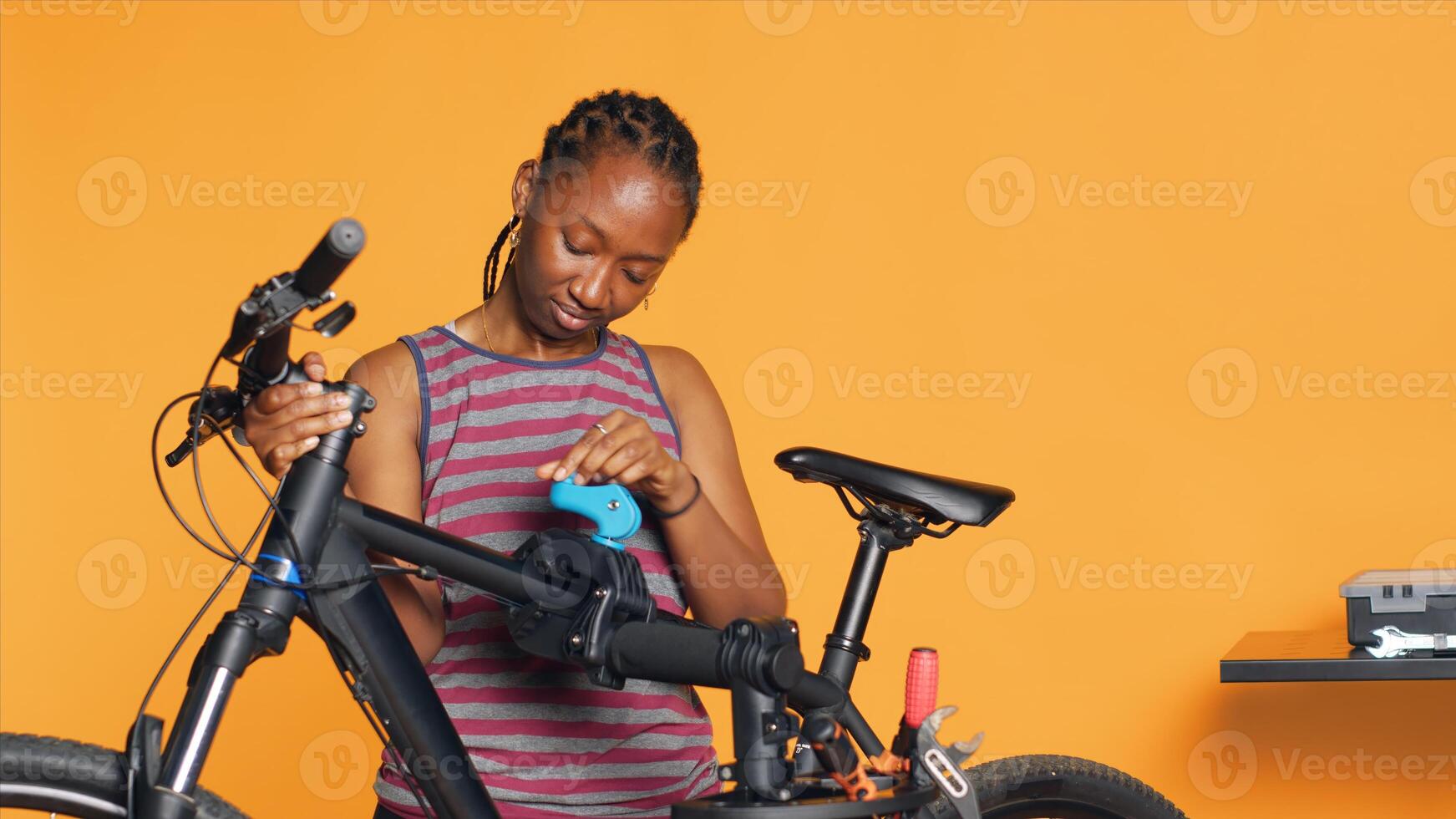 Atelier shop employee setting up bike repair stand before starting work on busted wheels, studio background. Professional securing bicycle on workstand before examining for damages, camera A photo