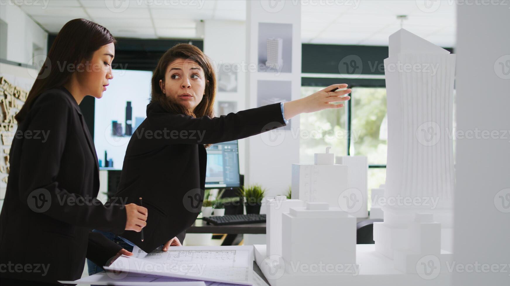 Cad experts examining architectural blueprints at agency, holding 3d printed building model to measure elements and shapes. Team of women architects studying property scale draft, coworking space. photo