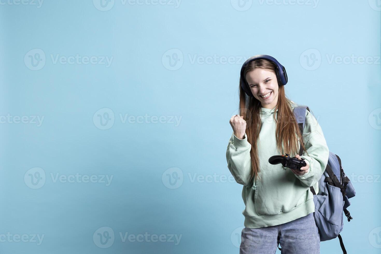 Euphoric woman playing intense gaming console game, celebrating win, isolated over studio background. Ecstatic young girl using controller, excited after being victorious in videogame photo