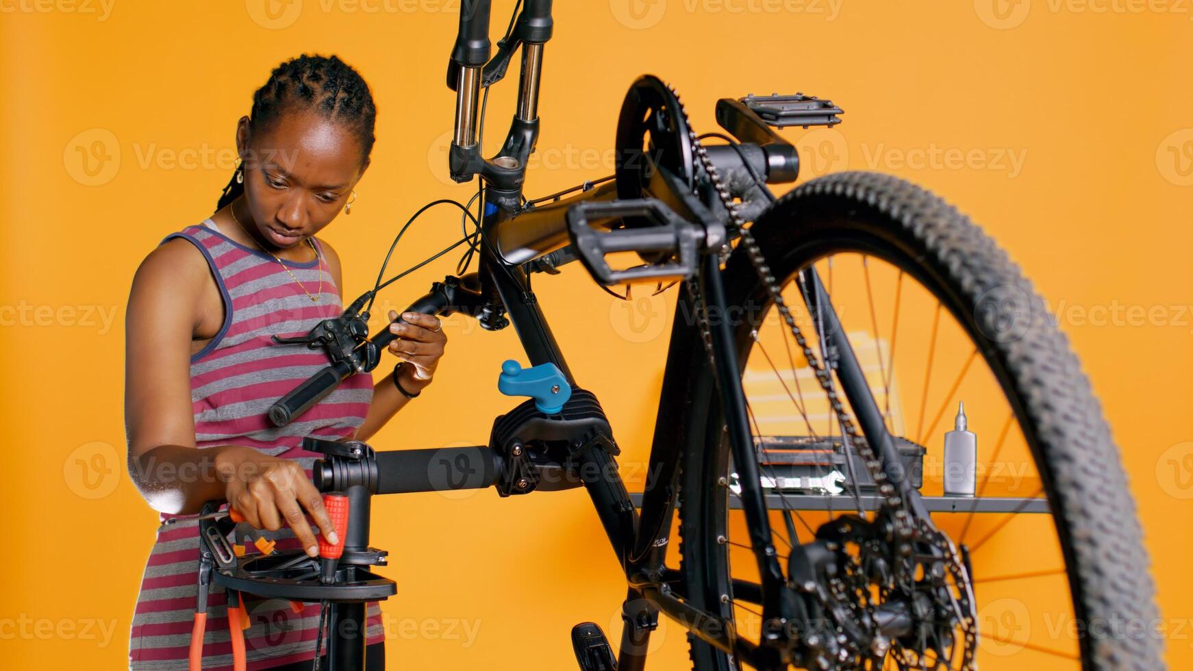 Engineer uses screwdriver to tighten brake levers screws on bicycle handlebars, examining components, studio background. Expert unscrewing defective bike parts in order to recondition them, studio B photo
