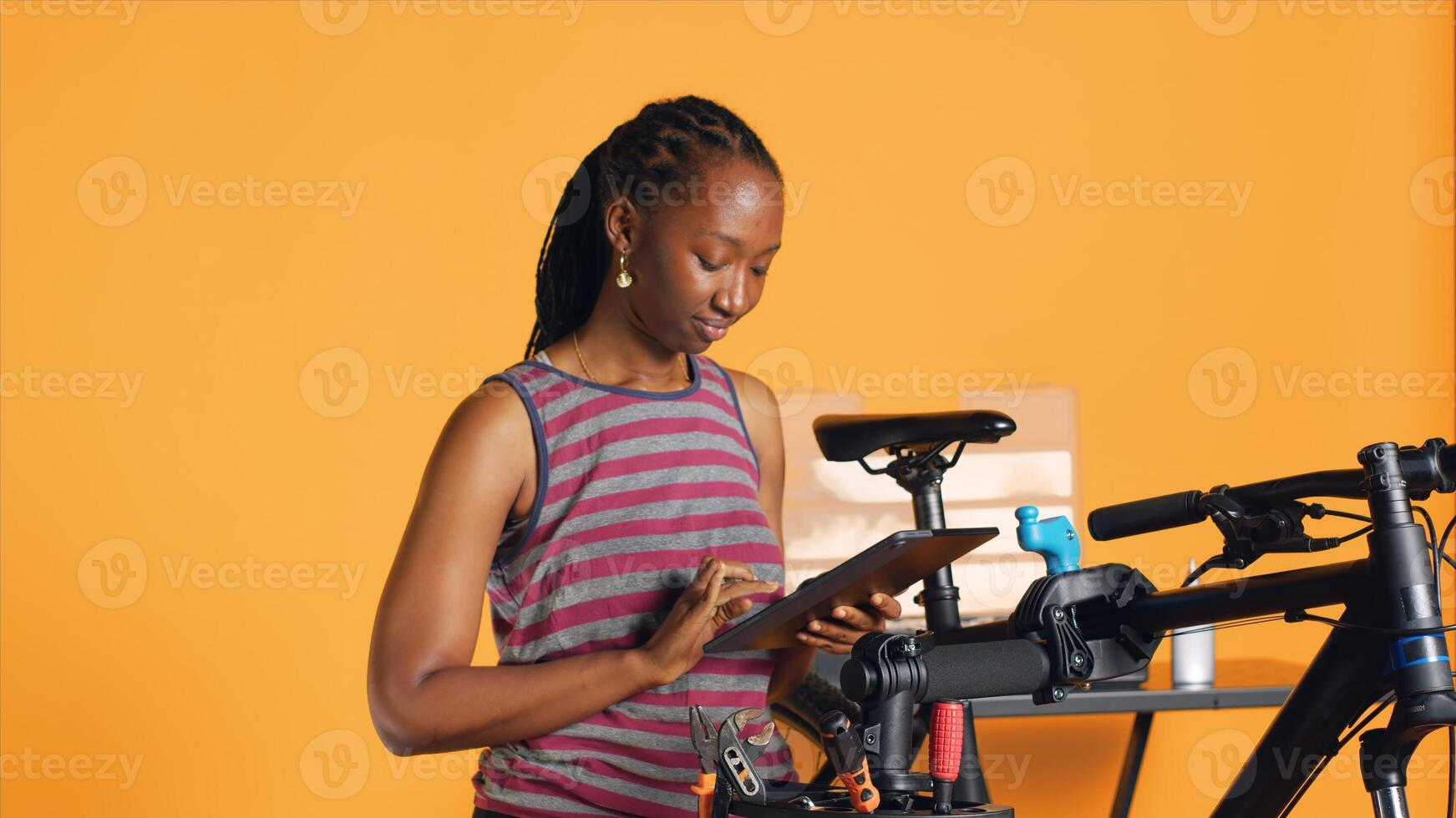 African american woman following online guide on tablet screen to learn how to fix malfunctioning bike components. BIPOC person educating herself online on diy tricks for repairing bicycles, camera A photo