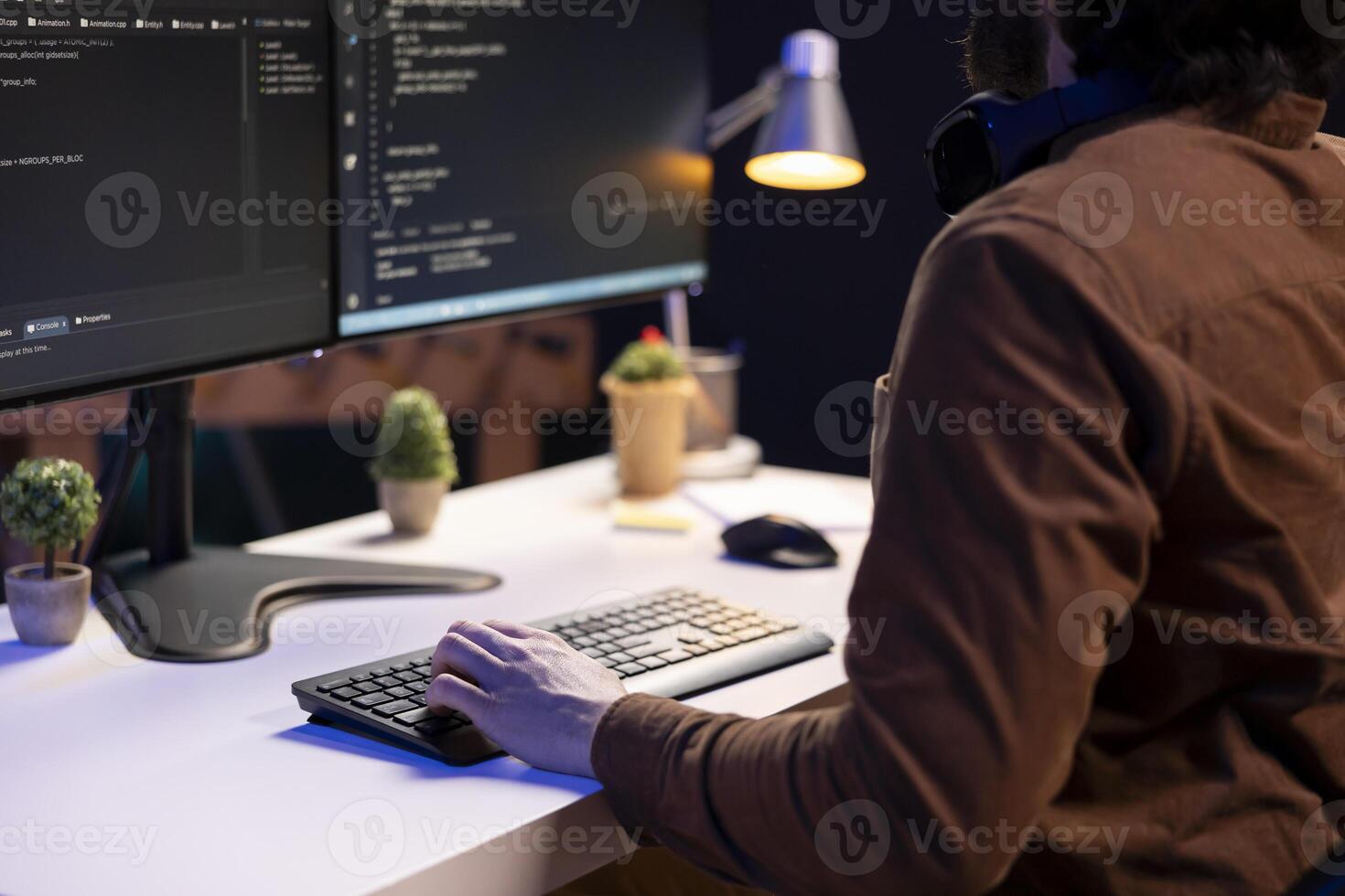 System administrator doing software debugging on PC at home, checking broken lines of code displayed on monitors. IT professional in living room fixing coding problems, typing on keyboard photo
