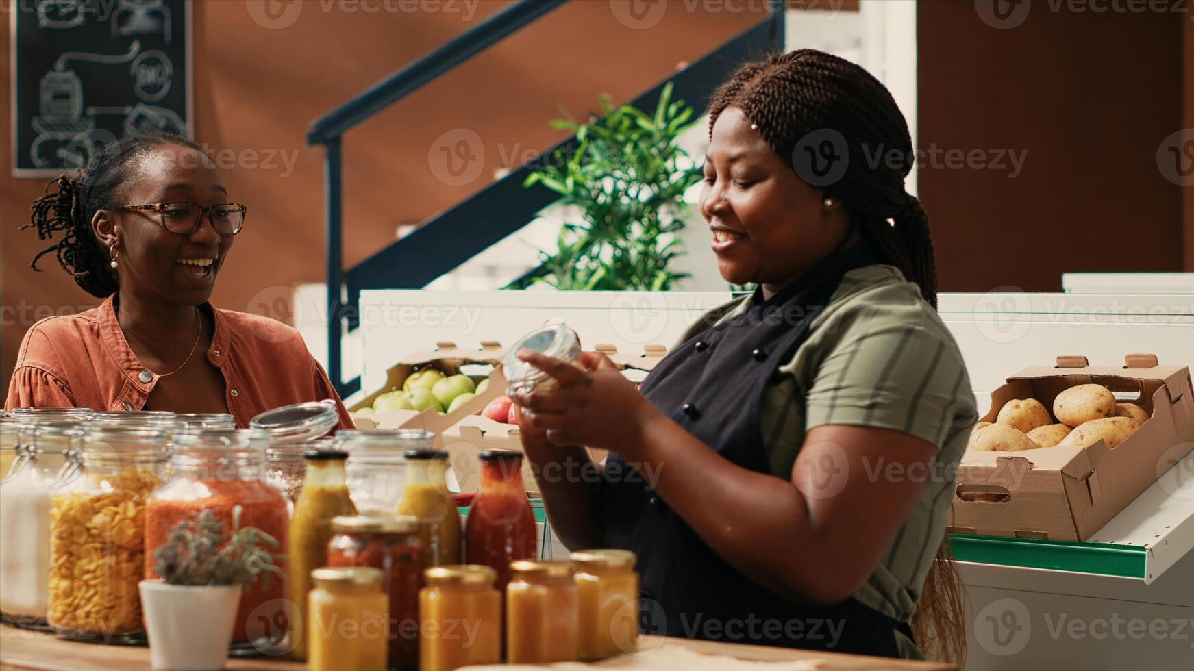 Merchant offering food sample to customer at farmers market, proving authentic natural taste of products before buying. African american business owner providing great service for shopper. photo