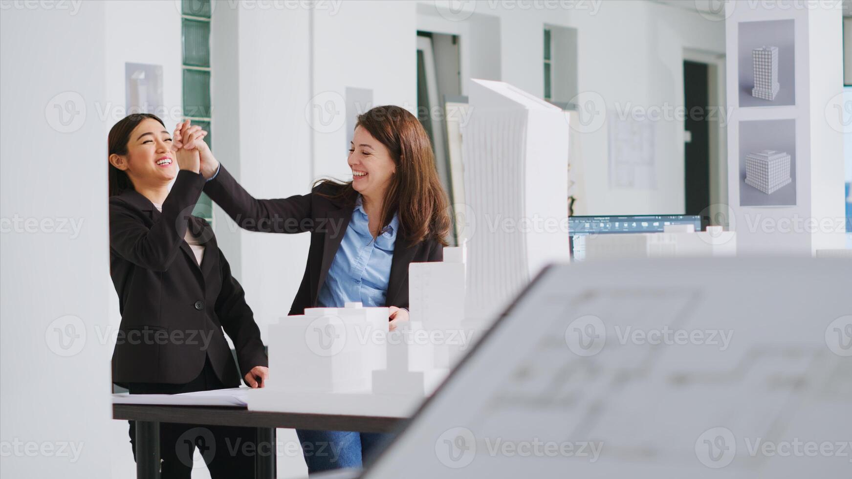 Architects doing high five gesture after finishing blueprints, feeling happy about translating measurements and determining scale elements for building development. Women solve task successfully. photo