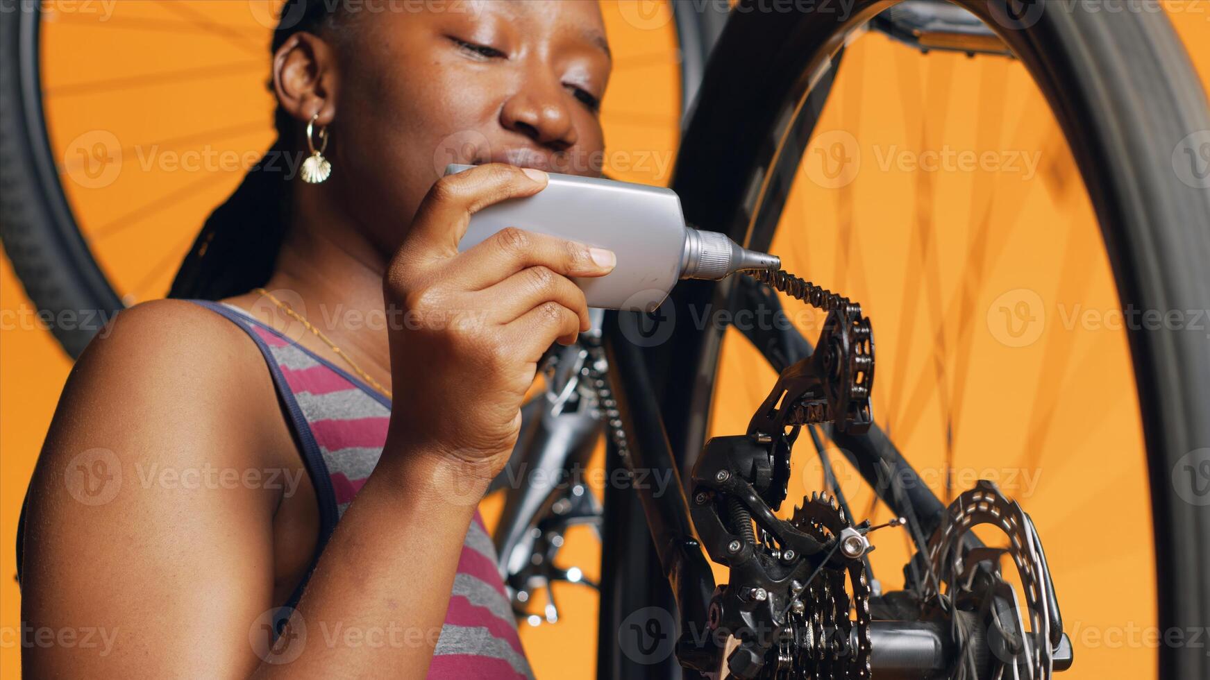 Experienced serviceman using specialized glue to mend defective bicycle chain, orange studio background. Worker applying adhesive on bike parts during inspection process, close up shot photo