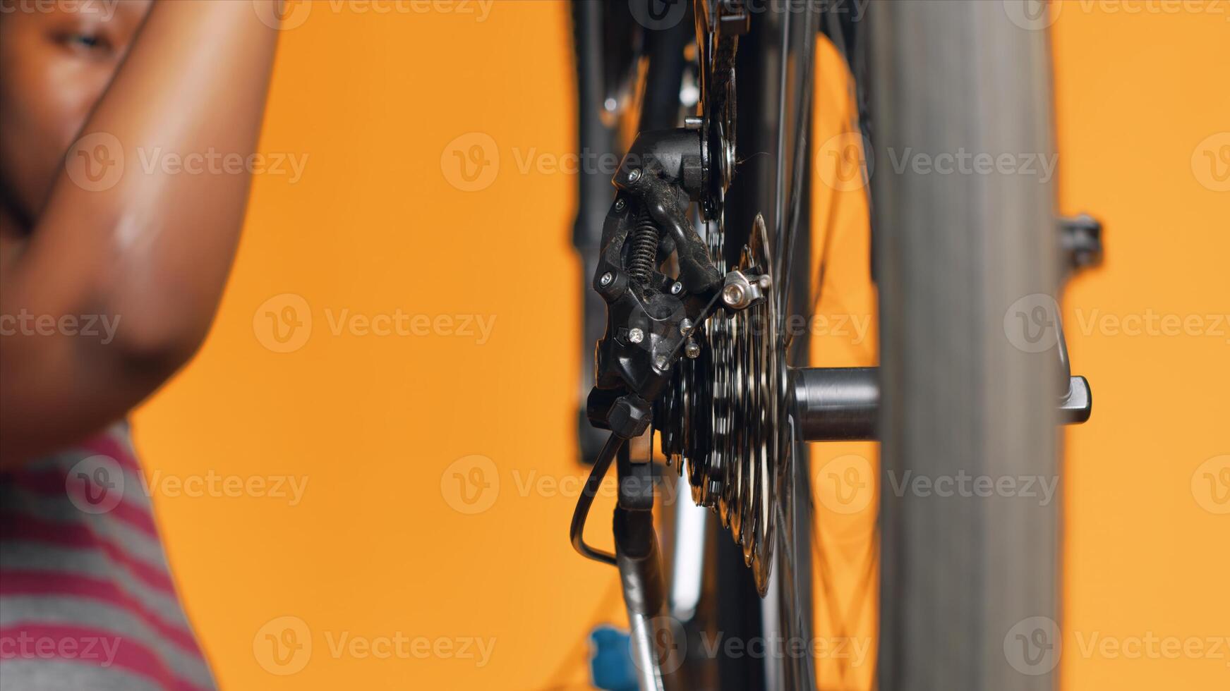 Close up shot of bike wheel being tested by woman doing servicing in studio background atelier shop. Technician fixing bicycle tires, checking for faults in break rotor and chain photo