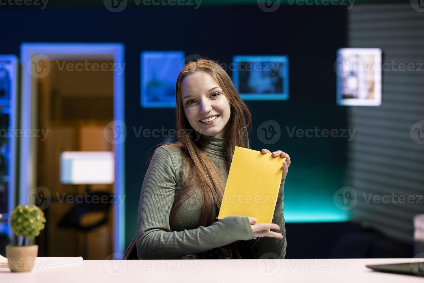 Upbeat gen Z content creator films review of book, presenting synopsis to audience. Joyful media star sponsored by publisher to show new novel release to subscribers photo