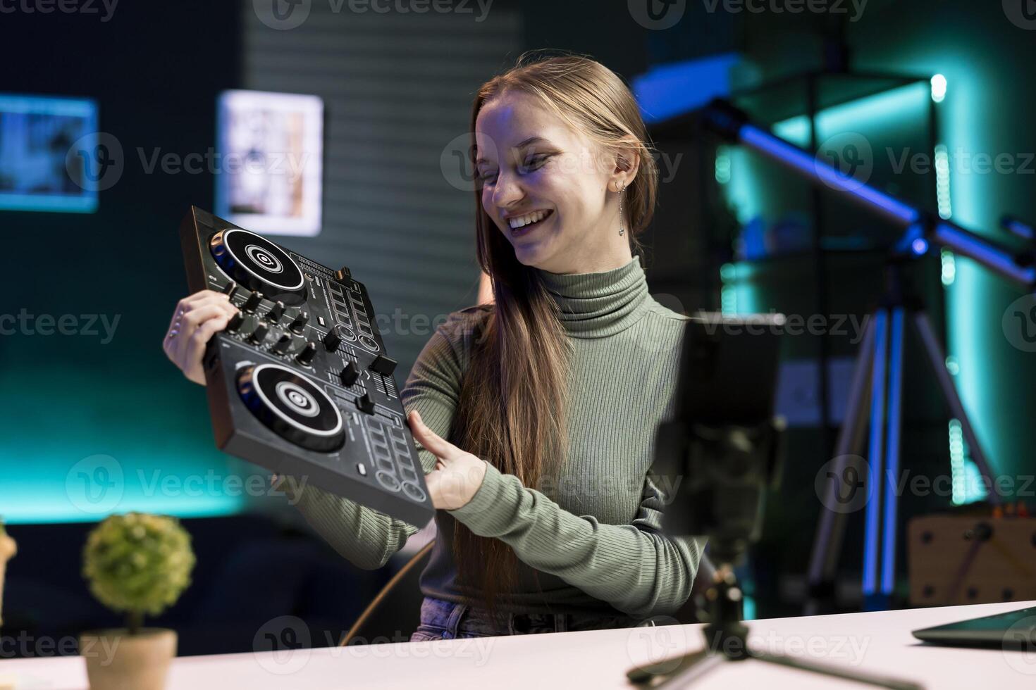 Joyous influencer filming DJ mixing tutorial in home studio, showing examples of sampling on sound controller to viewers. Joyful gen Z entertainer excited to review modern musical device for audience photo