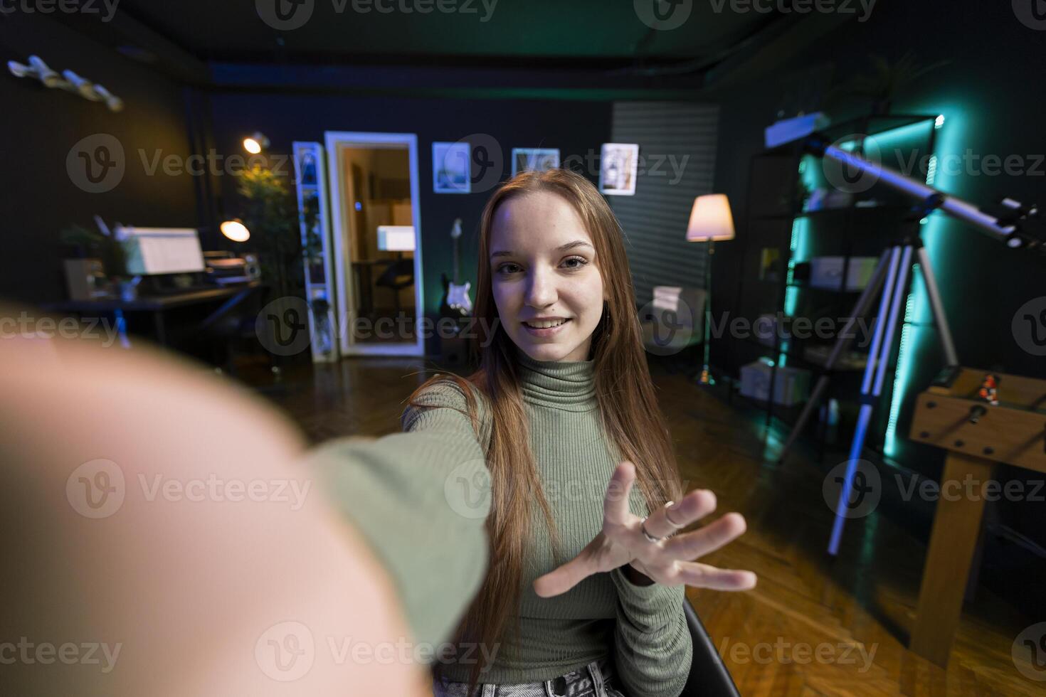 POV of gen Z teenager recording introductory with cellphone on selfie stick, inviting viewers to subscribe to channel. Influencer in home studio uses selfie camera to film herself photo