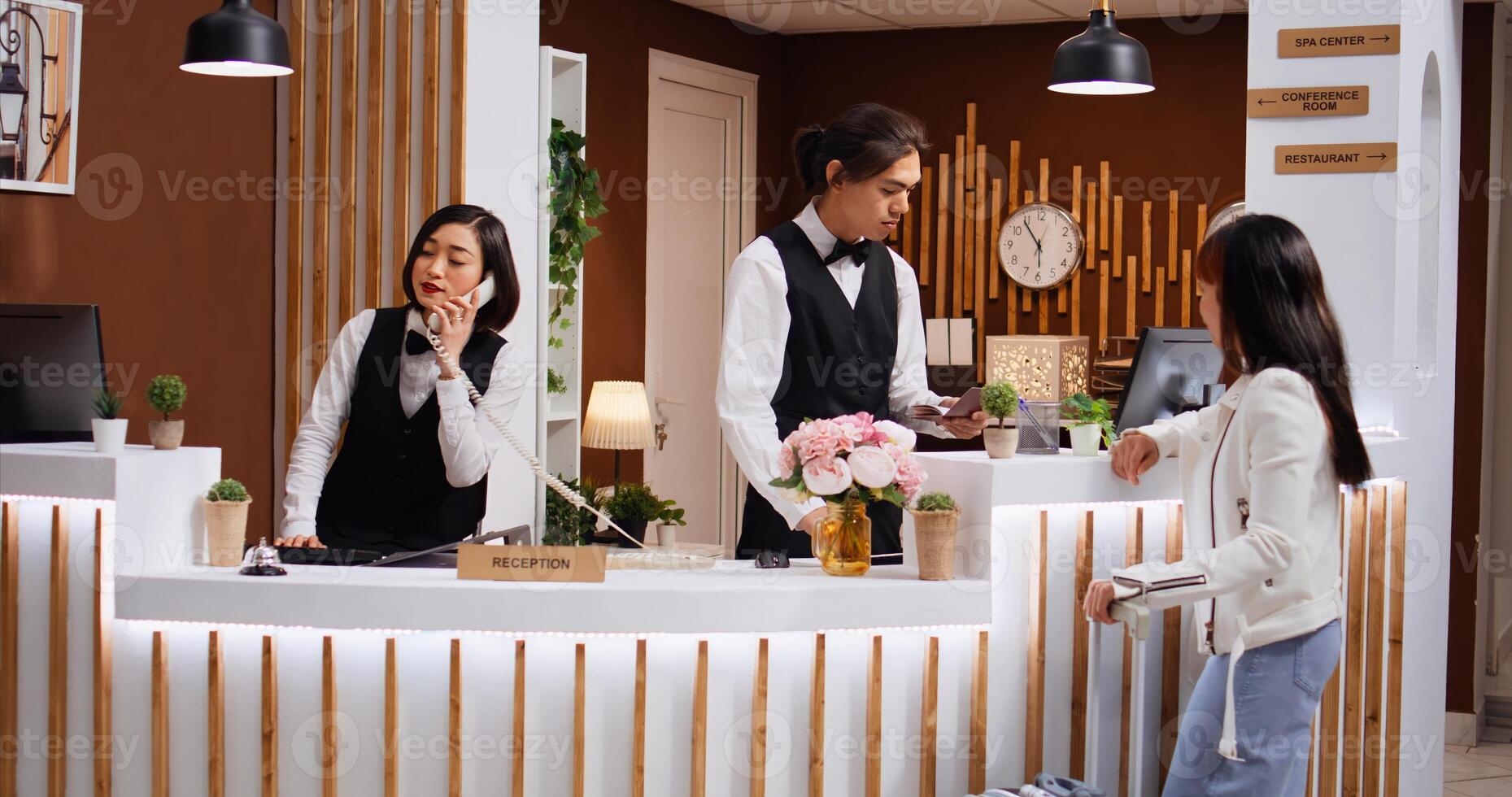 Employee looking at passport info for guest identification, undergoing check in process at front desk. Receptionist does tourist id verification and providing great concierge services for her. photo