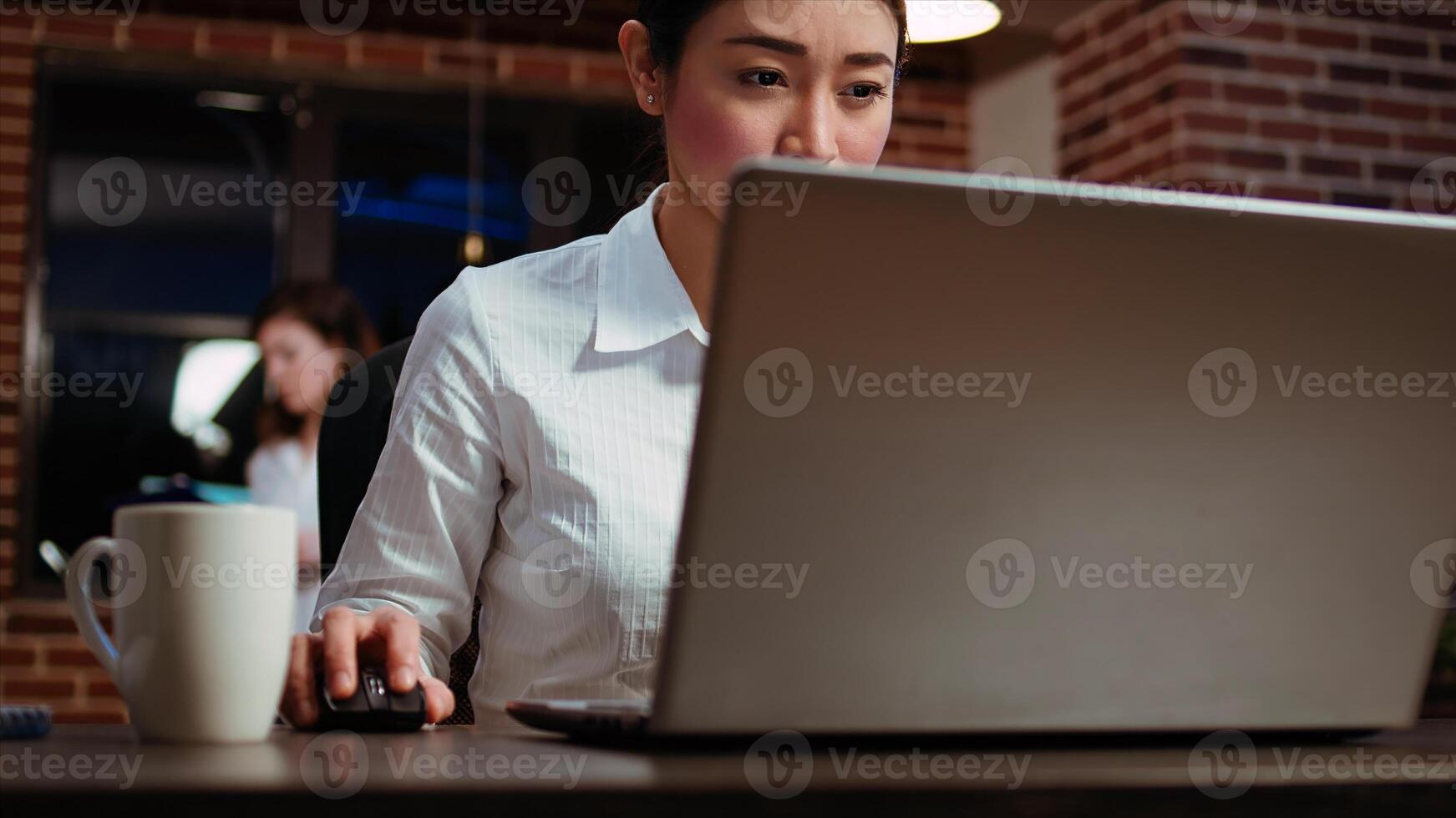 Businesswoman doing computer tasks for team project in office overnight, reading information on screen. Panning shot of worker working late at night, typing on laptop keyboard, camera B photo