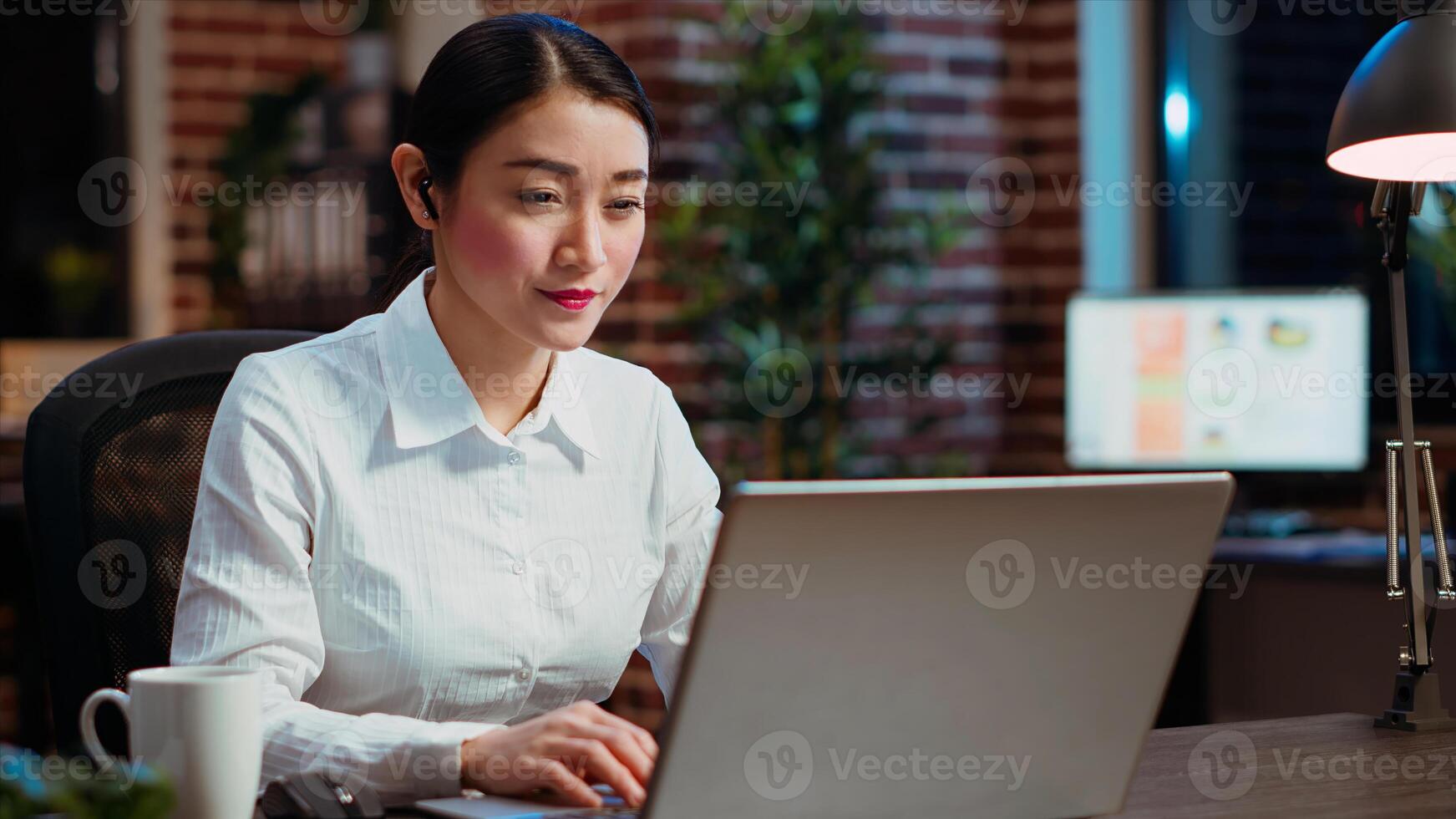 Cheerful businesswoman greeting colleagues during business meeting on videocall in office. Employee speaking in remote videoconference telework call to discuss company matters photo