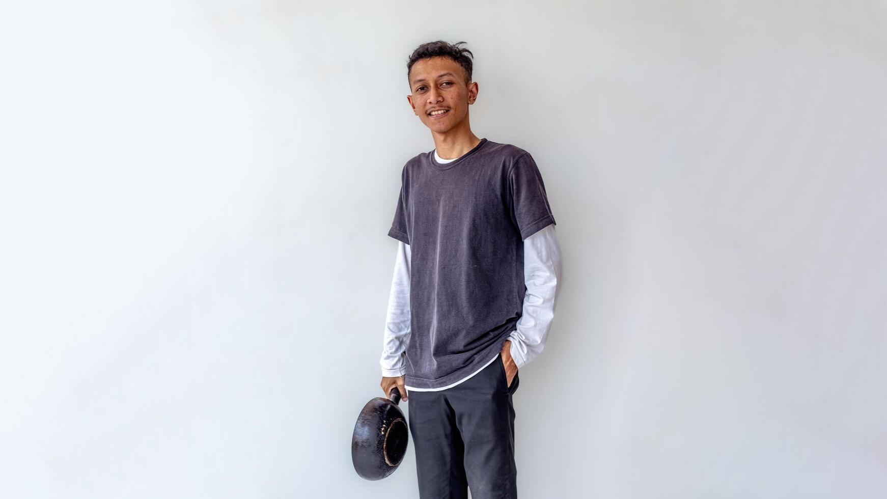 a young man standing proudly while holding a frying pan like a chef isolated on white background photo