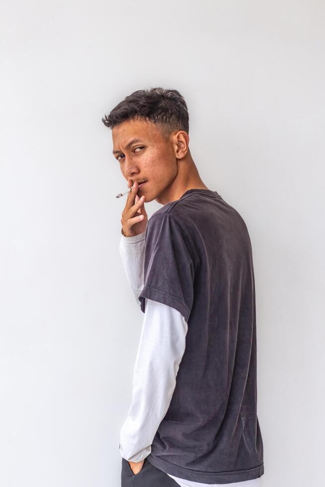 a young man wearing a gray t-shirt with glasses is smoking isolated on white background. suitable for health and environmental concepts photo