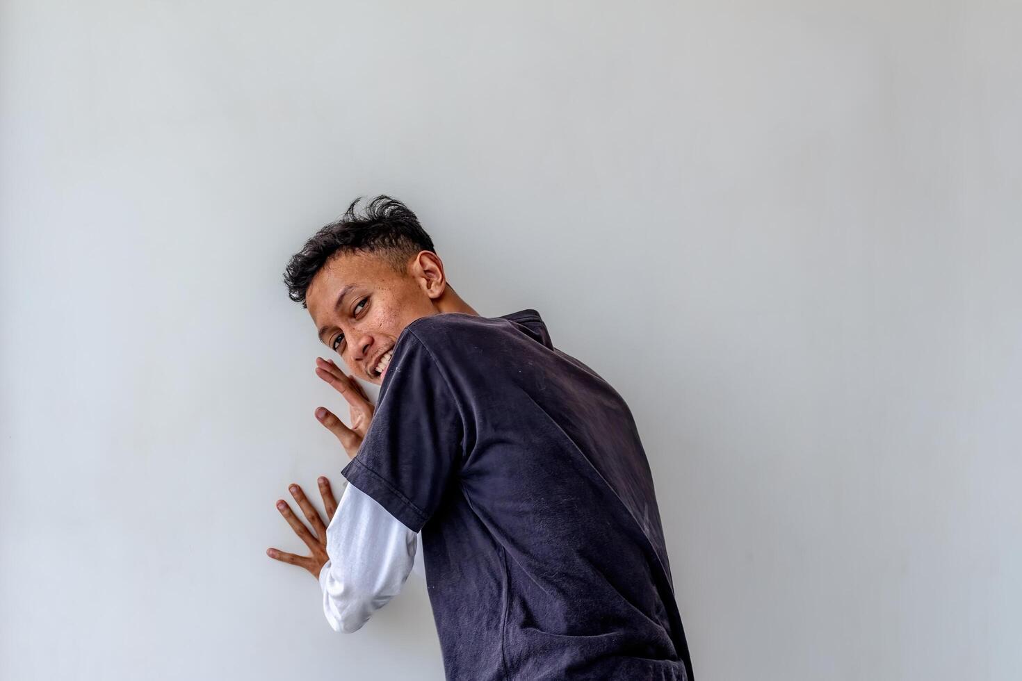 Adult man pushing against a plain white wall while facing away, isolated on a white background. The image captures a dynamic pose, ideal for themes related to strength, effort, and fitness. photo