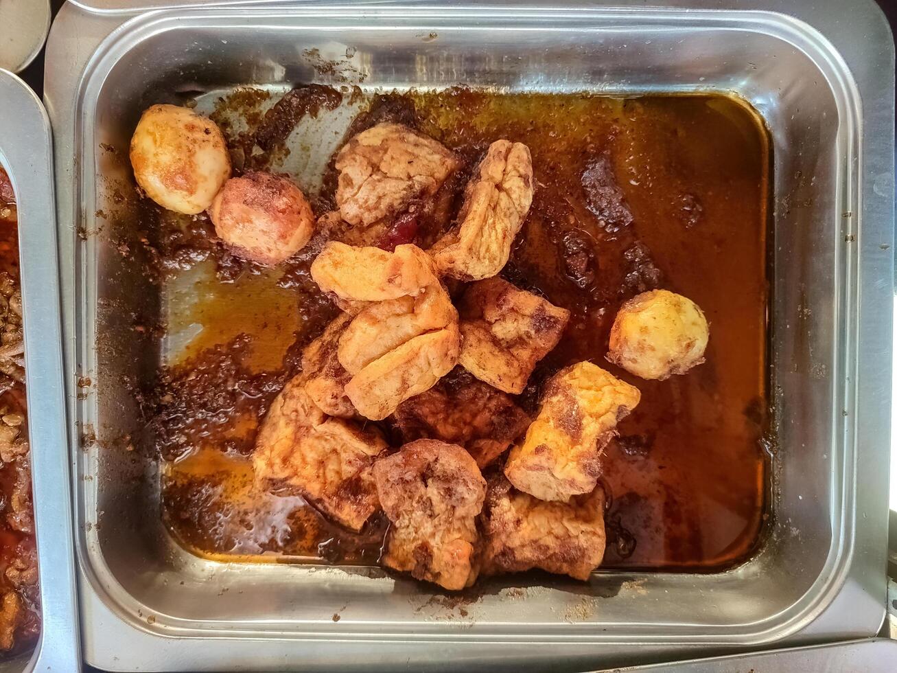 A traditional Balinese dish of deep fried tofu and hard boiled eggs simmered in a rich and spicy sauce. photo