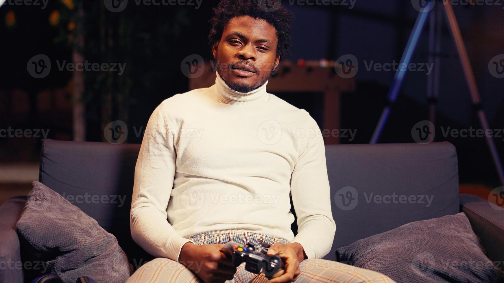 Portrait of livid gamer raging in frustration after losing mission while playing videogame on gaming console. BIPOC player on cozy couch furiously yelling after getting destroyed in game and failing to win level photo