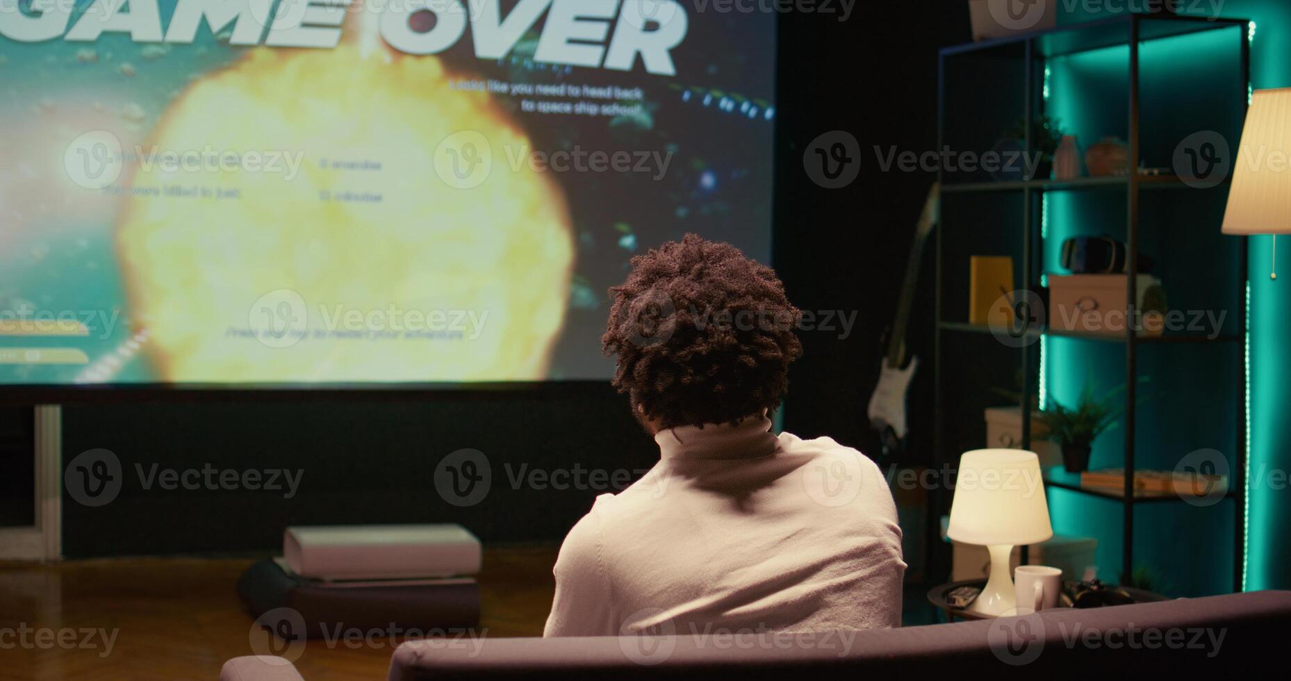 Upset african american gamer raging after losing game, playing on ultrawide smart TV. Man in living room feeling angry and shouting after his spaceship exploded, defeated in videogame photo