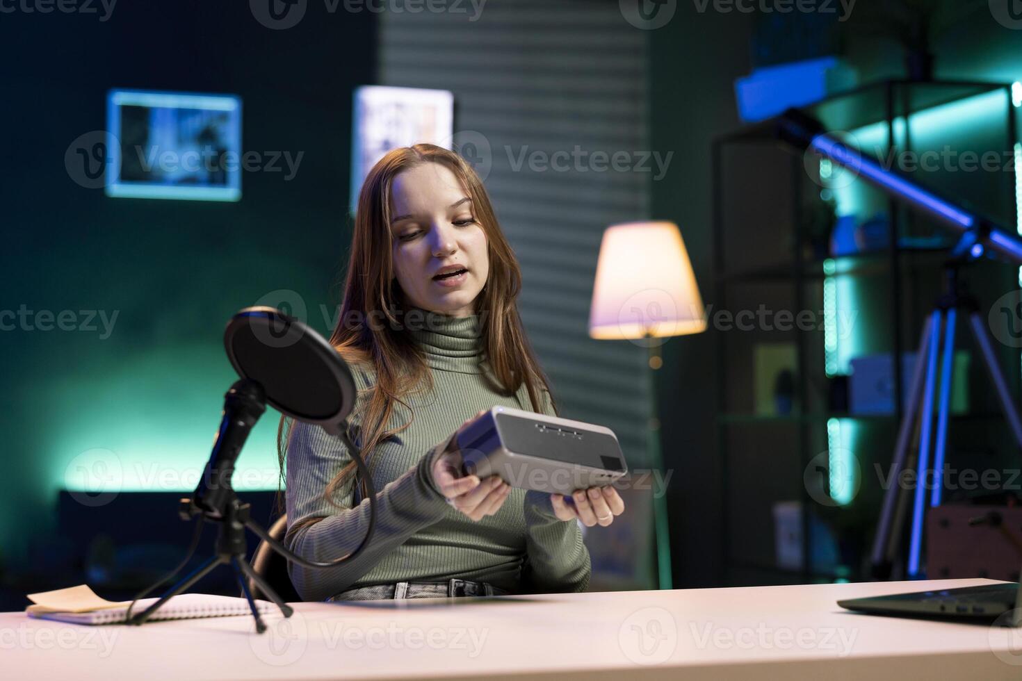 Gen Z internet star filming about best bluetooth music playing devices of the year. Happy young tech content creator recording portable speaker review, evaluating audio quality photo