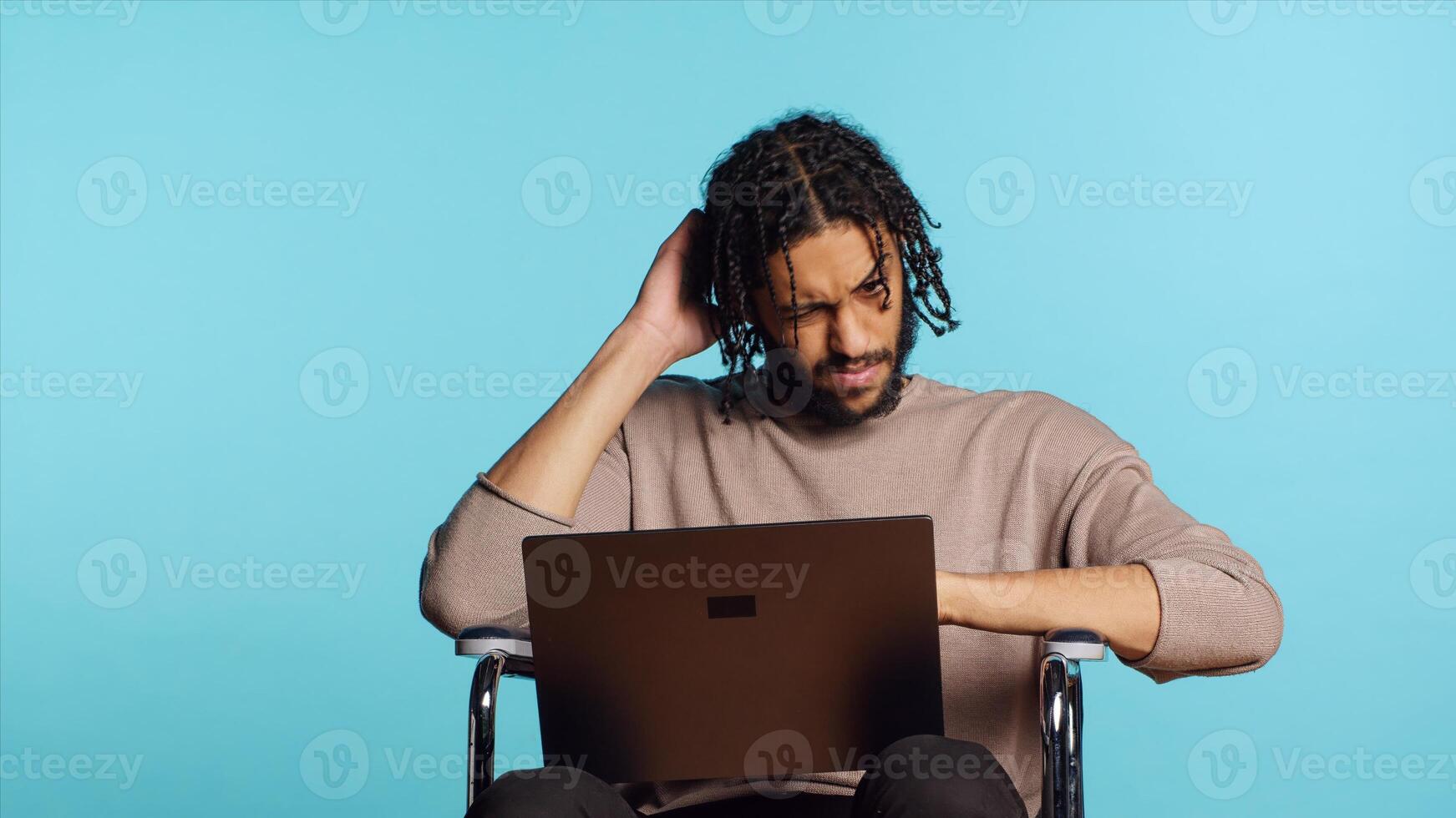 Middle Eastern man composing email, typing on laptop keyboard, struggling to think of what to write. BIPOC person sending mail online, brainstorming message idea, studio background, camera A photo