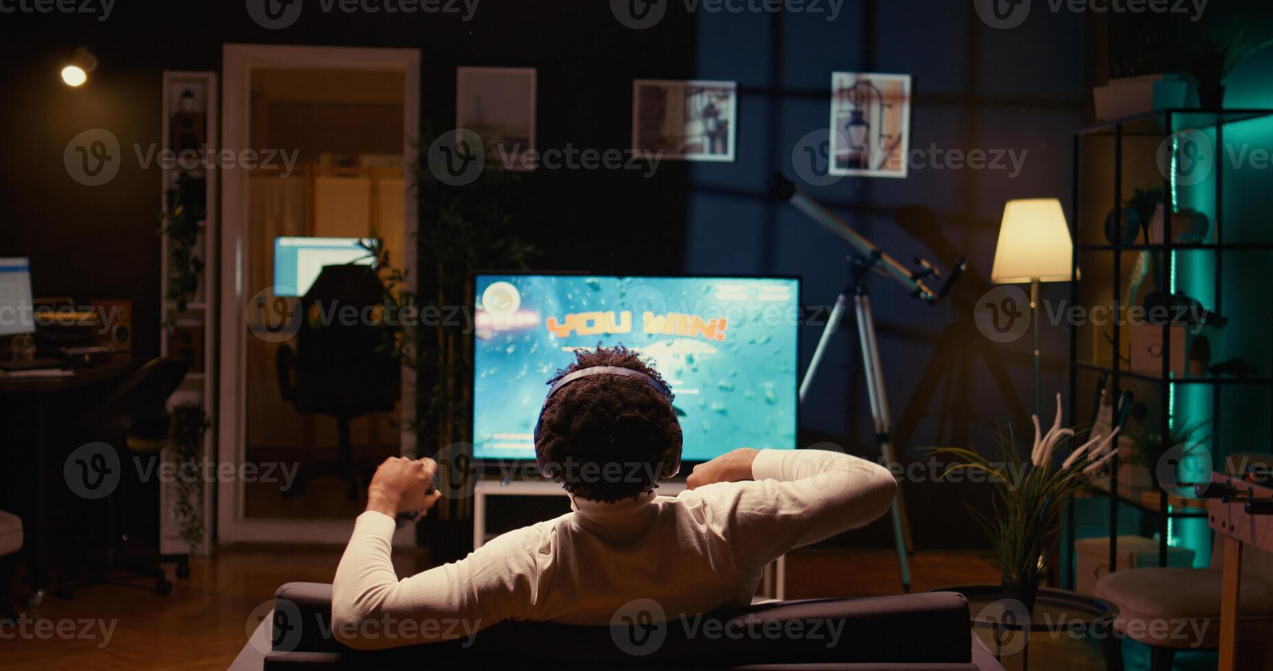 African american gamer winning after destroying all enemy spacecrafts and finishing level in SF game. Player victorious in videogame displayed on ultrawide TV after defeating boss and saving galaxy photo