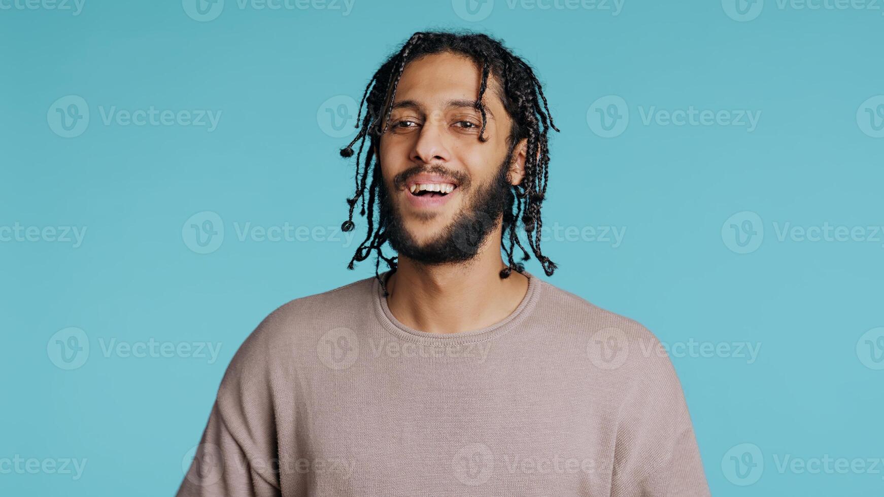 Approving smiling Middle Eastern man happily clapping hands, satisfied with accomplishments. BIPOC person cheering, doing praising gesture, isolated over blue studio background, camera B photo