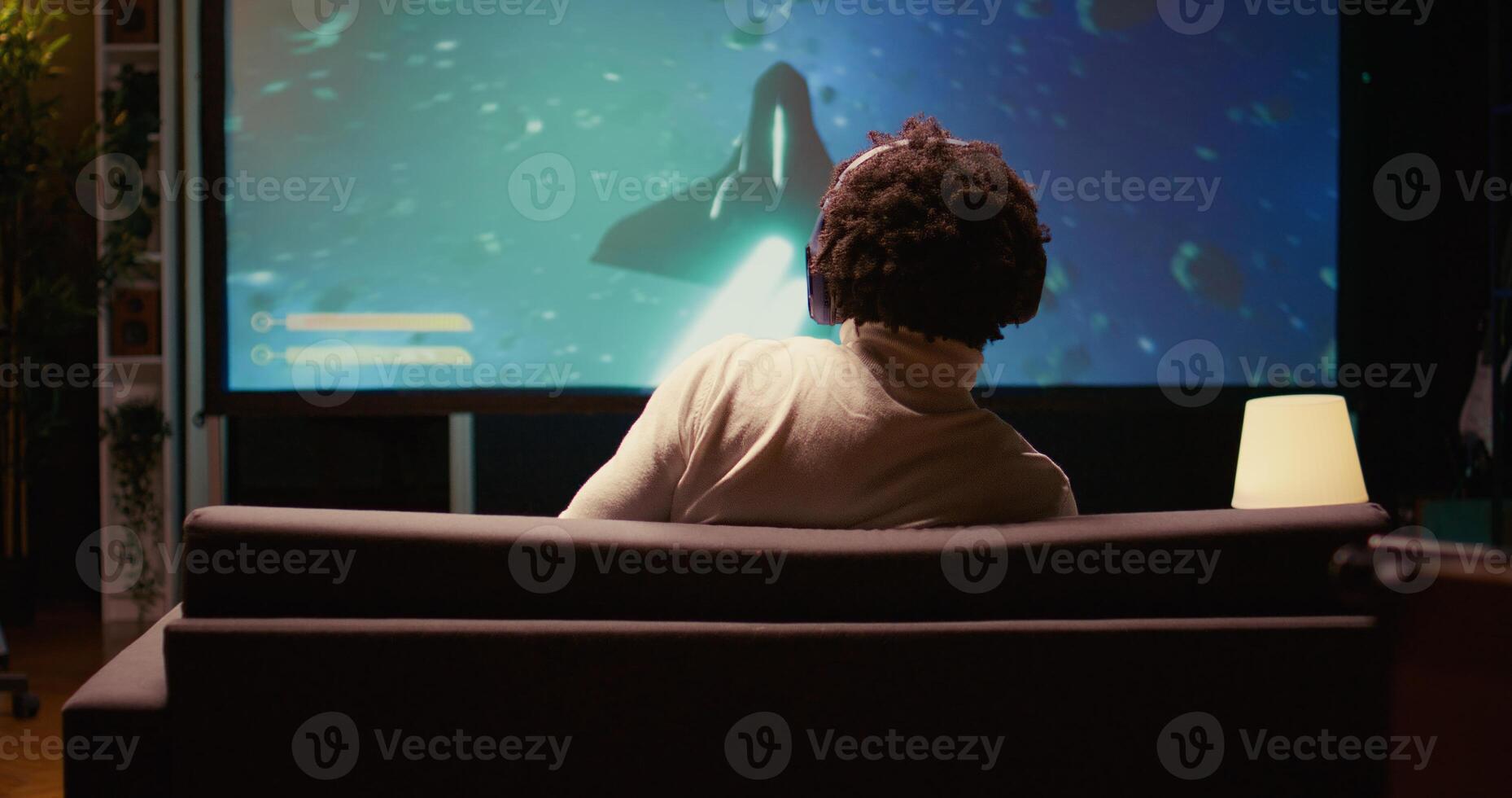 Man in cozy apartment using cloud gaming service to play demanding science fiction videogame on TV. Player enjoying high quality ray tracing graphics, streaming game online, zoom in close up shot photo