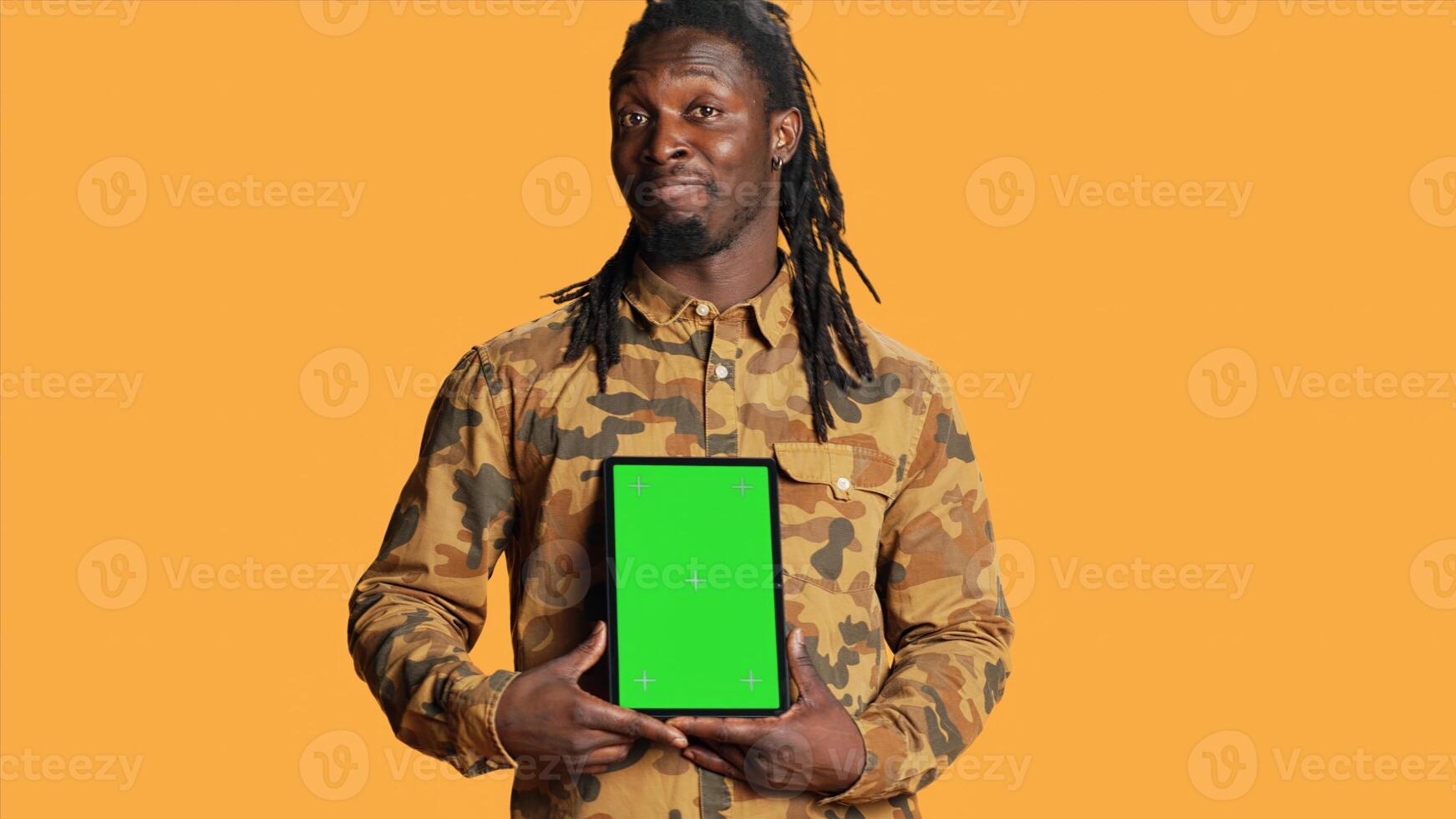 African american adult with greenscreen on gadget, presenting isolated chromakey display and smiling in front of camera. Young adult holding mobile device with copyspace blank layout. photo