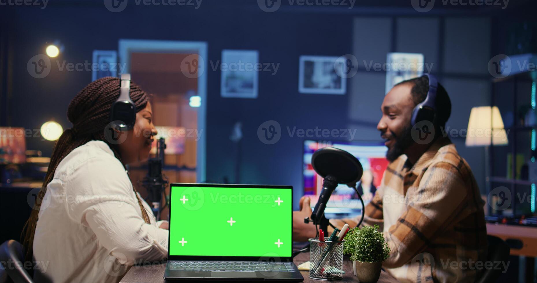 Green screen laptop next to woman laughing during comedy focused podcast, entertained by funny man. Mockup notebook near talking show interviewer telling jokes to audience watching at home photo