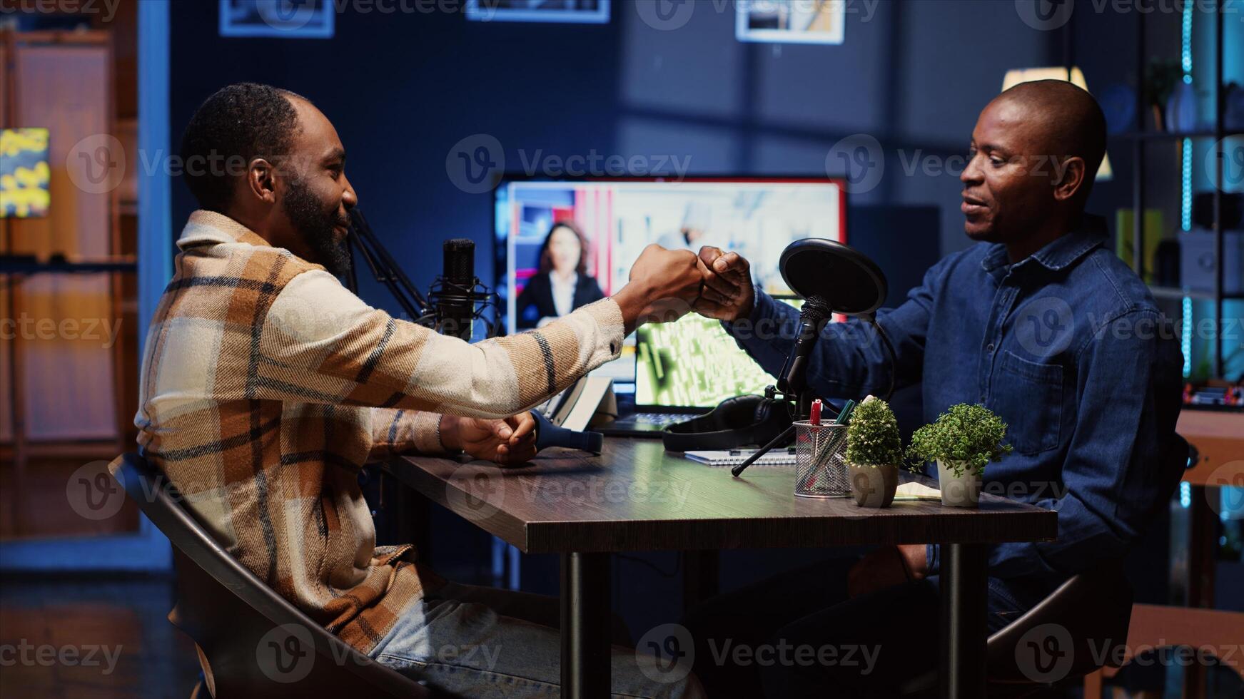 African american man invited to podcast, welcomed by friendly host, participating in entertaining discussion in studio. Cheerful guest fist bumping and saluting online comedy show presenter photo