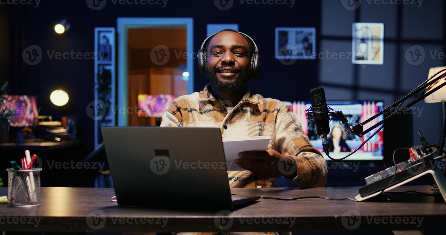 Smiling man arriving in studio, greeting audience, broadcasting live using professional equipment with high sound quality. Vlogger putting headphones on, talking with social media followers photo