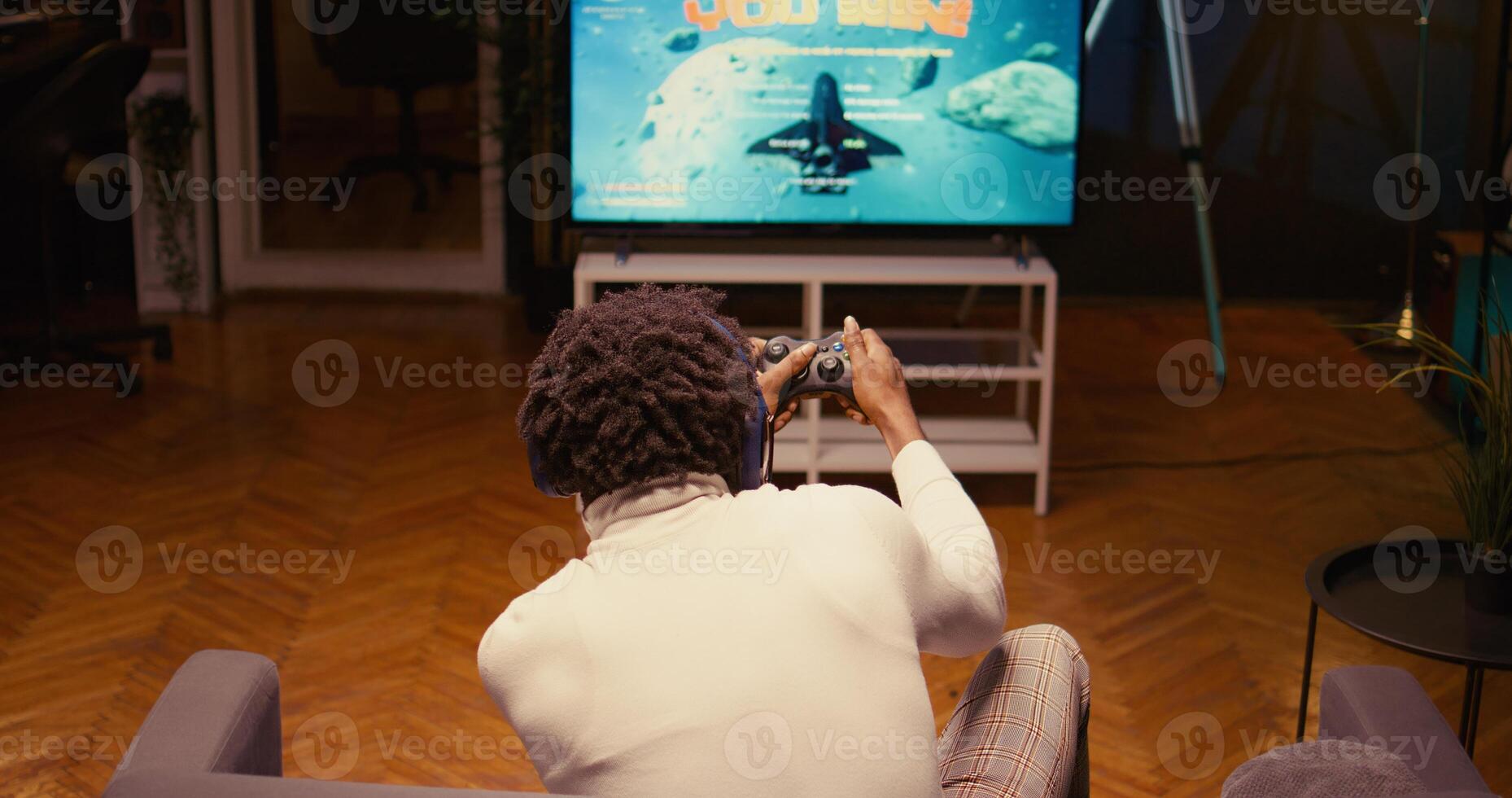 BIPOC gamer receiving winner screen on smart TV after killing all foes in science fiction game. Player celebrating after being victorious in SF videogame on console attached to television set photo