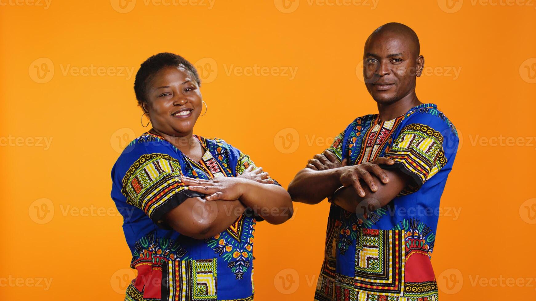 Confident ethnic couple posing in studio with colorful clothes, presenting traditional african american attire and being proud about their culture. Smiling husband and wife with arms crossed. photo