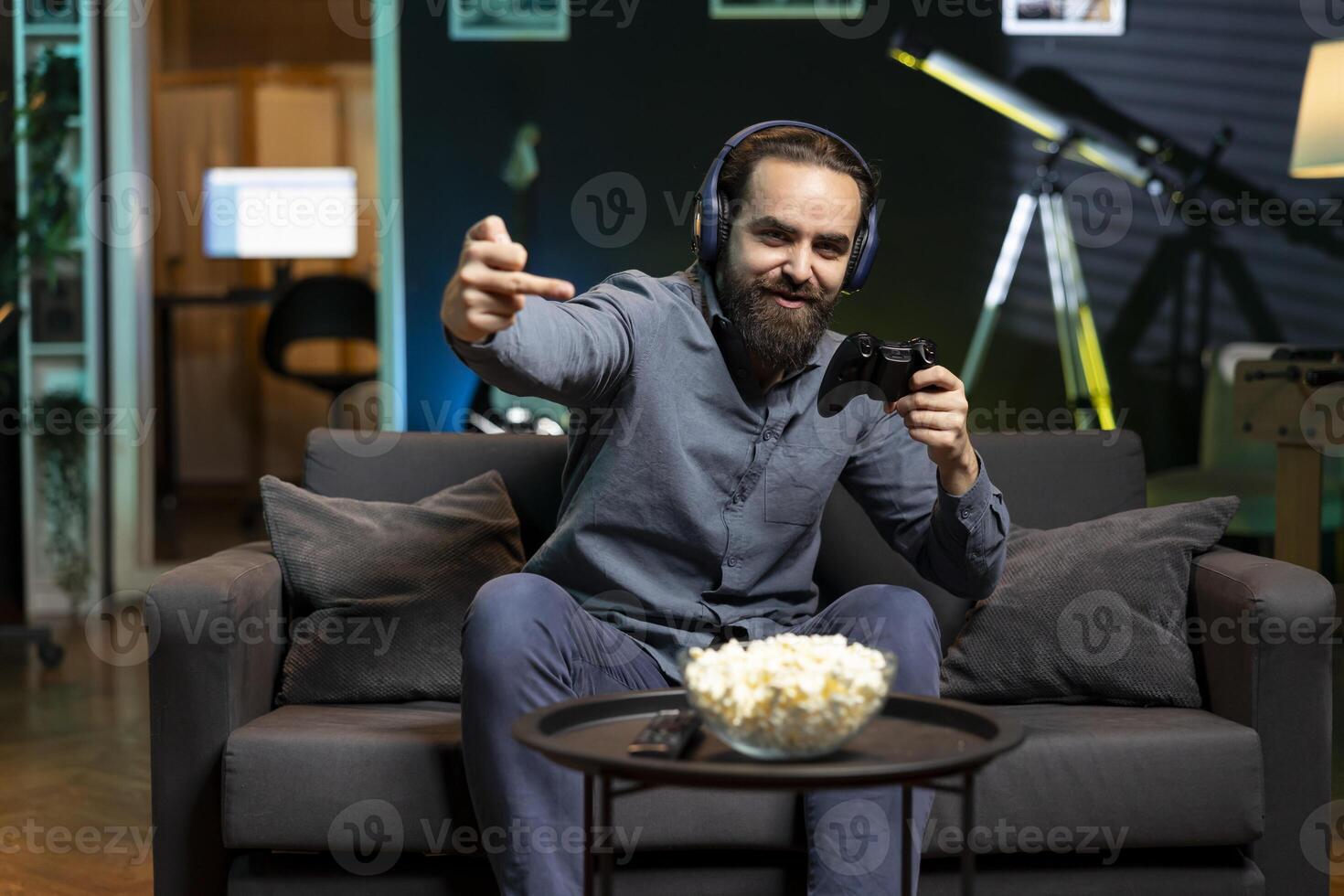 Cheerful man showing middle finger signs, celebrating videogame victory after conquering all rival players. Gamer doing crass hand gestures, excited after winning game, displaying happiness emotions photo