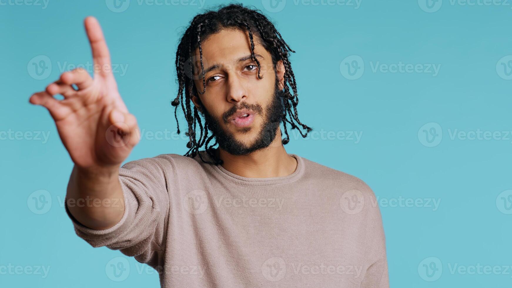 Assertive Middle Eastern man doing stop hand gestures. Annoyed BIPOC person doing firm halt sign gesturing, wishing to end concept, isolated over blue studio background, camera B photo