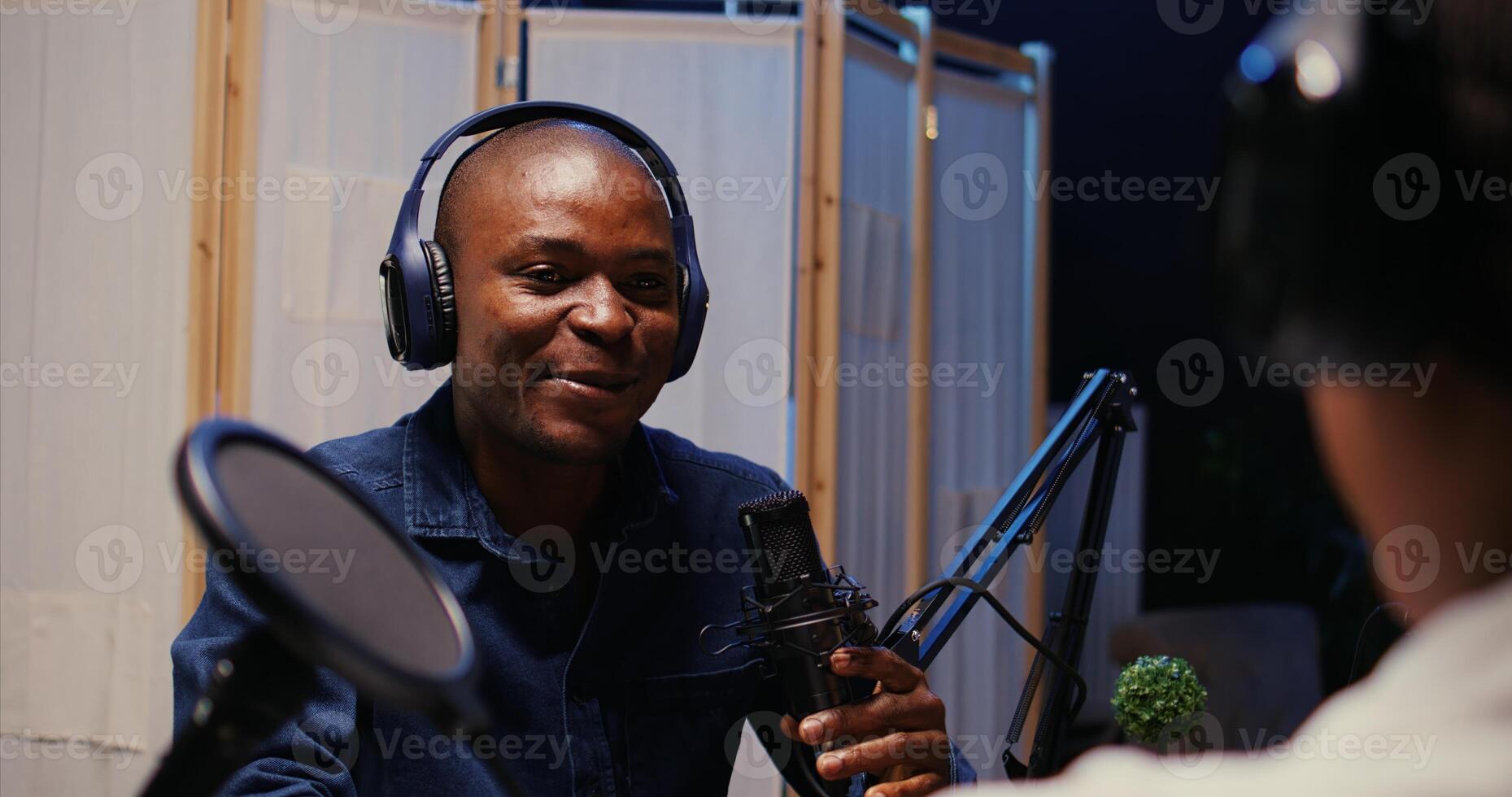 African american man recording podcast using high tech audio equipment to interview guest, ensuring flawless sound quality for subscribers listening at home interested in interviewee photo