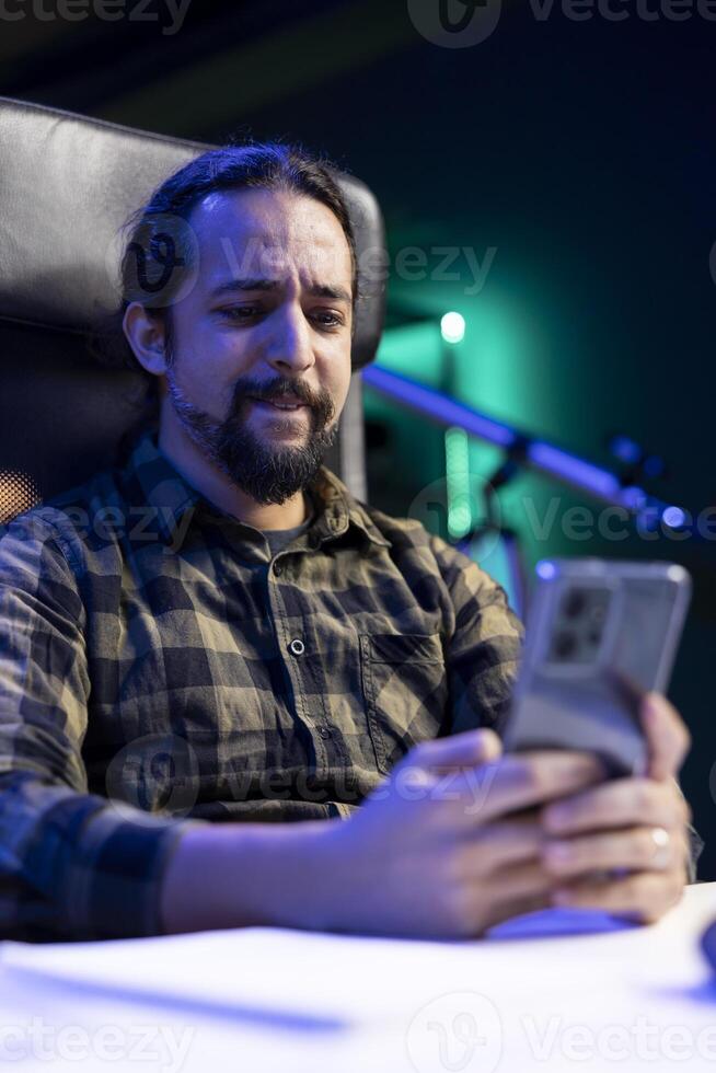 Young man with a concentrated expression, texting on his cell phone, sending messages, and checking social media. Focused male individual browsing the internet on his mobile device. photo