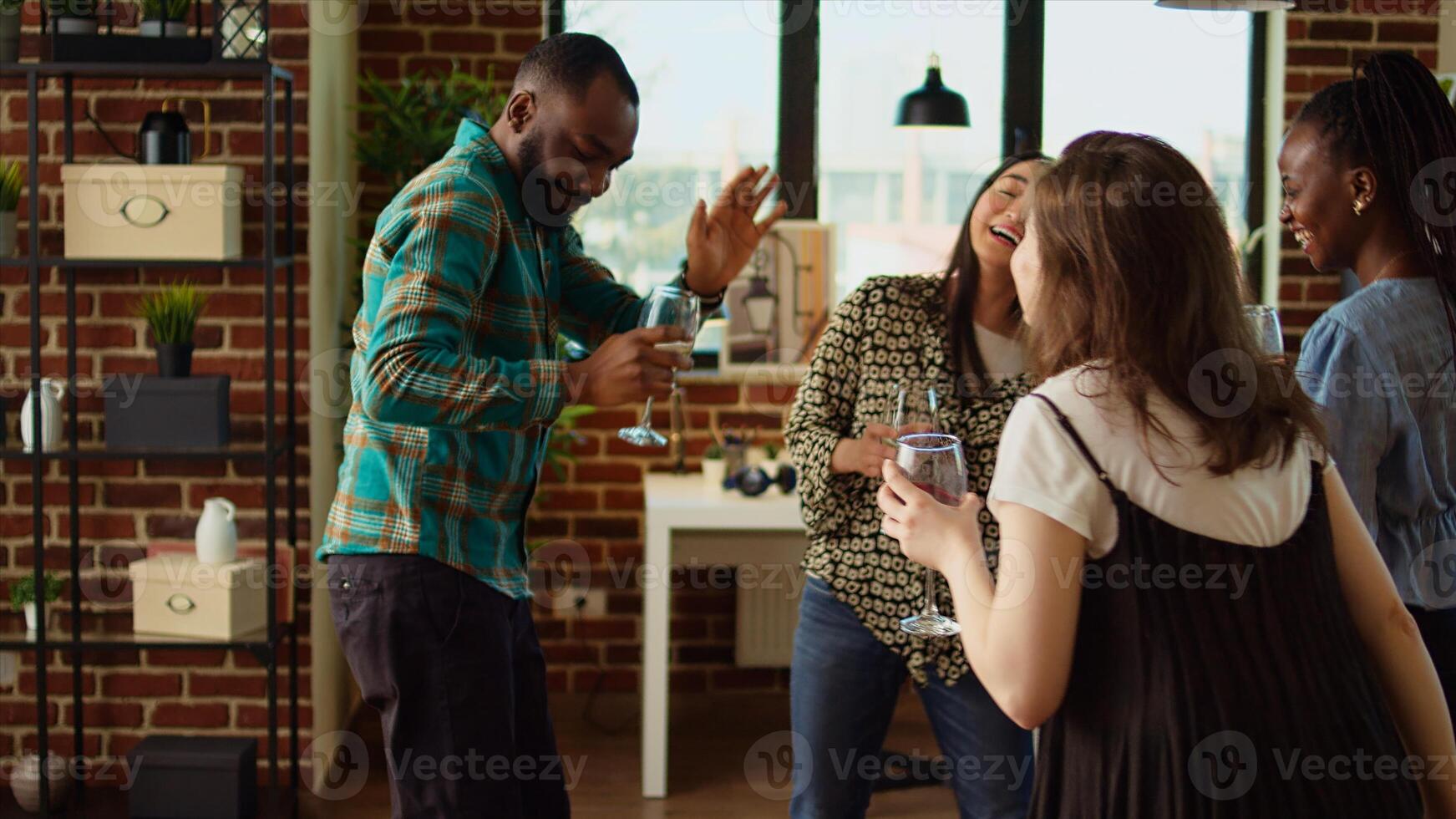 Multiracial mix of guests at home party sharing laughter and dance moves, creating vibrant atmosphere in living room. Friends dancing on hiphop beats during weekend hangout, shaking their hips photo