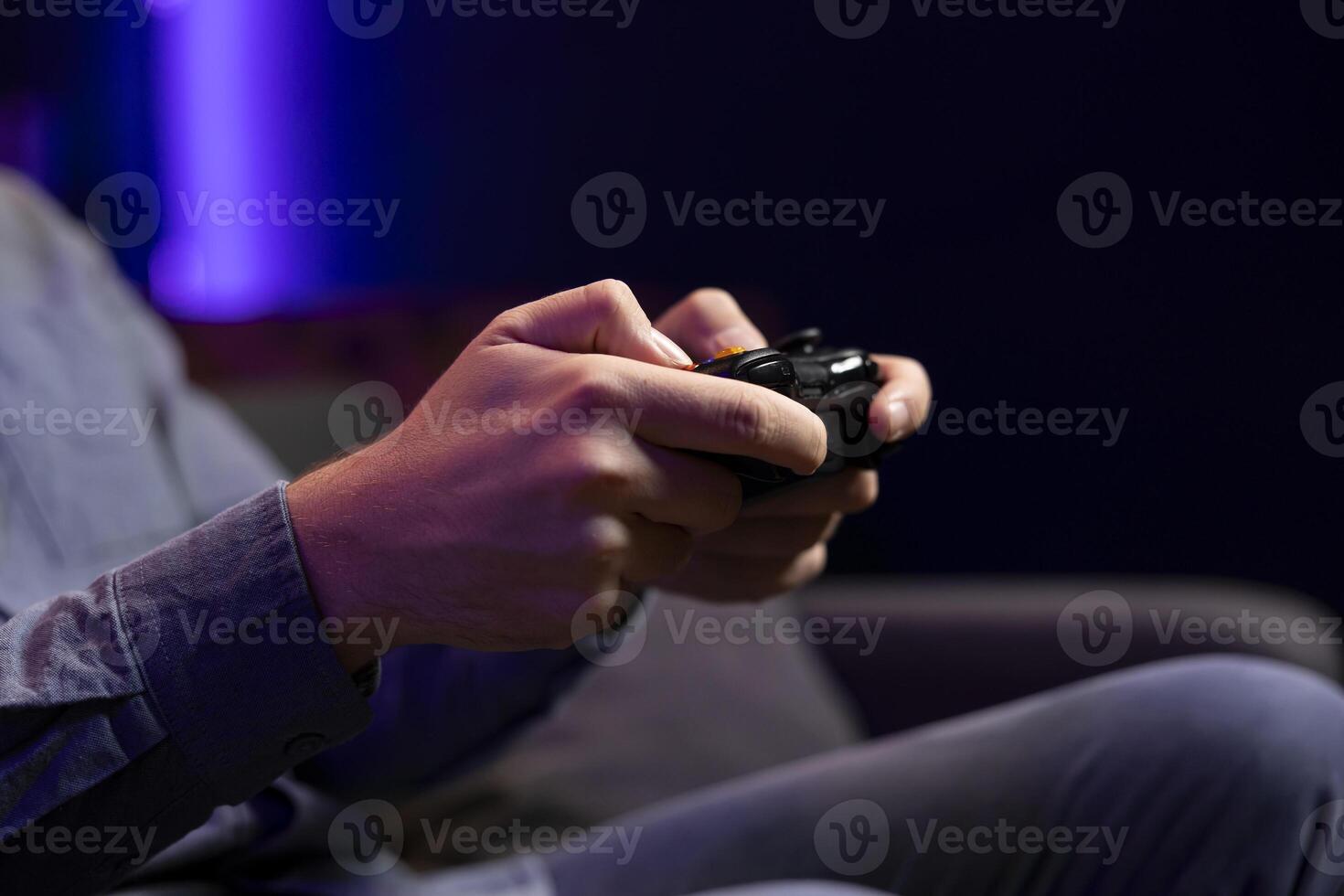 Close up shot of gamepad controller in man hands playing intense online videogame in neon illuminated living room. Gamer participating in internet esports competition, playing on gaming console photo