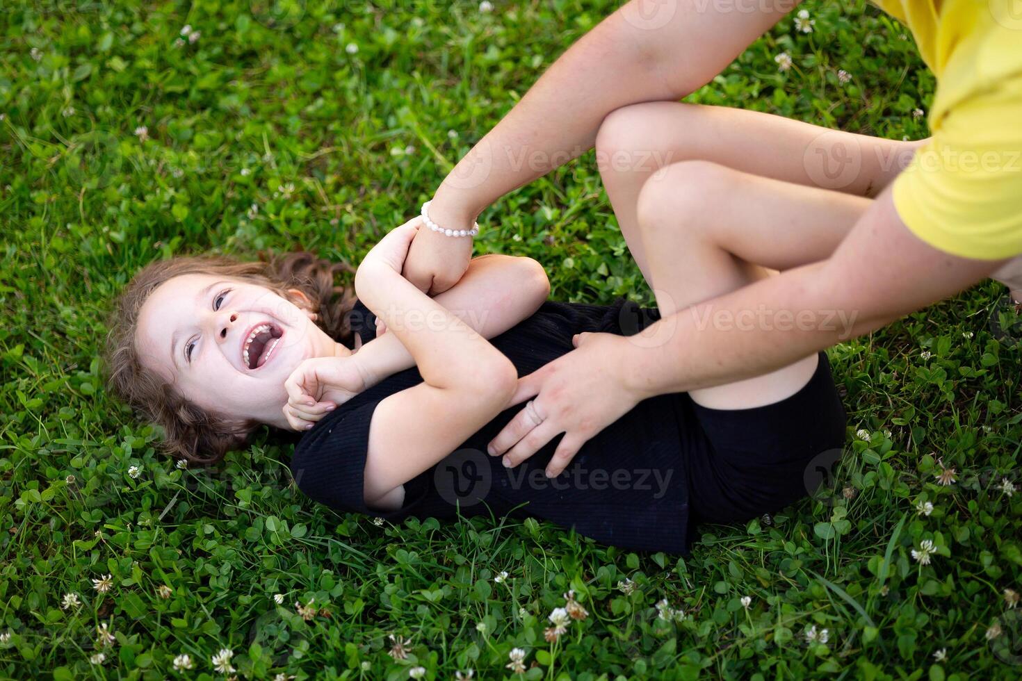 a little girl is lying on the grass playing with her mother. Cheerful and happy child photo