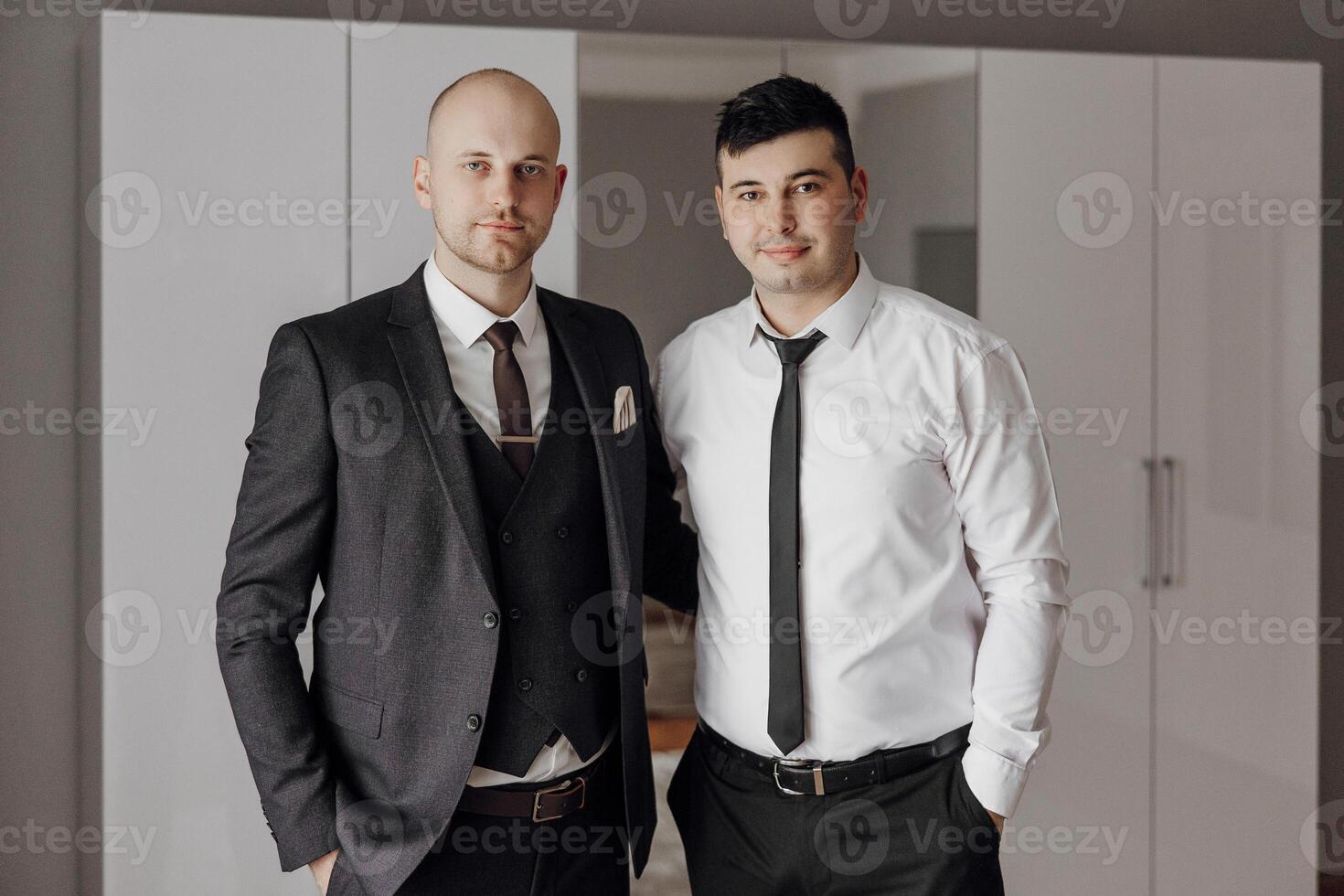Two men in suits and ties pose for a photo. Scene is professional and formal photo