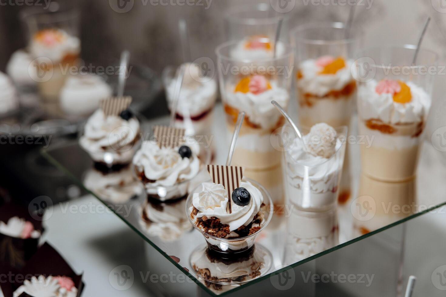 A table with a variety of desserts in plastic cups, including some with blueberries and raspberries photo