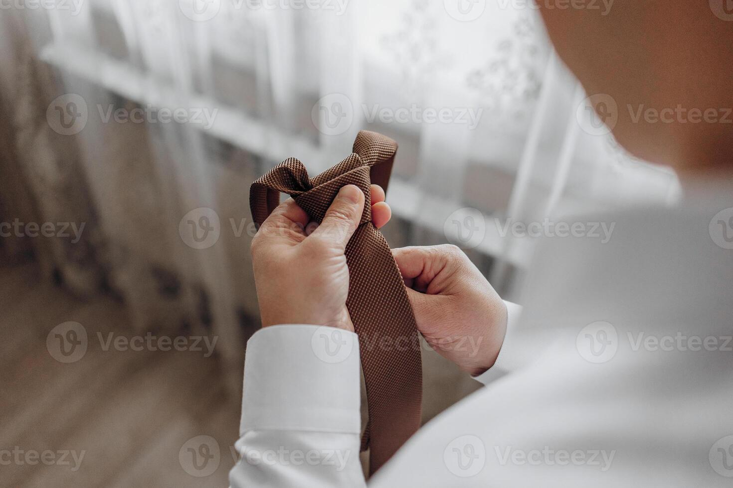 un hombre es consiguiendo Listo a Corbata su atar. él es participación el Corbata en su manos y él es enfocado en el tarea. concepto de preparación y atención a detalle foto