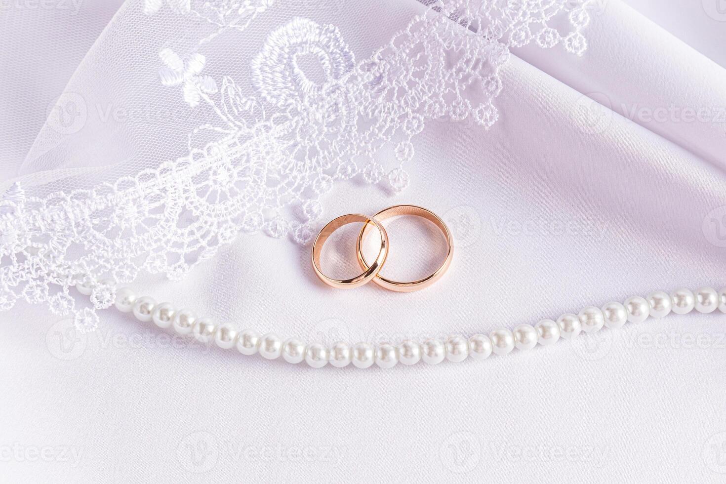 Beautiful wedding arrangement with two gold wedding rings white satin fabric, lace veil, pearl beads. wedding card, invitation. photo